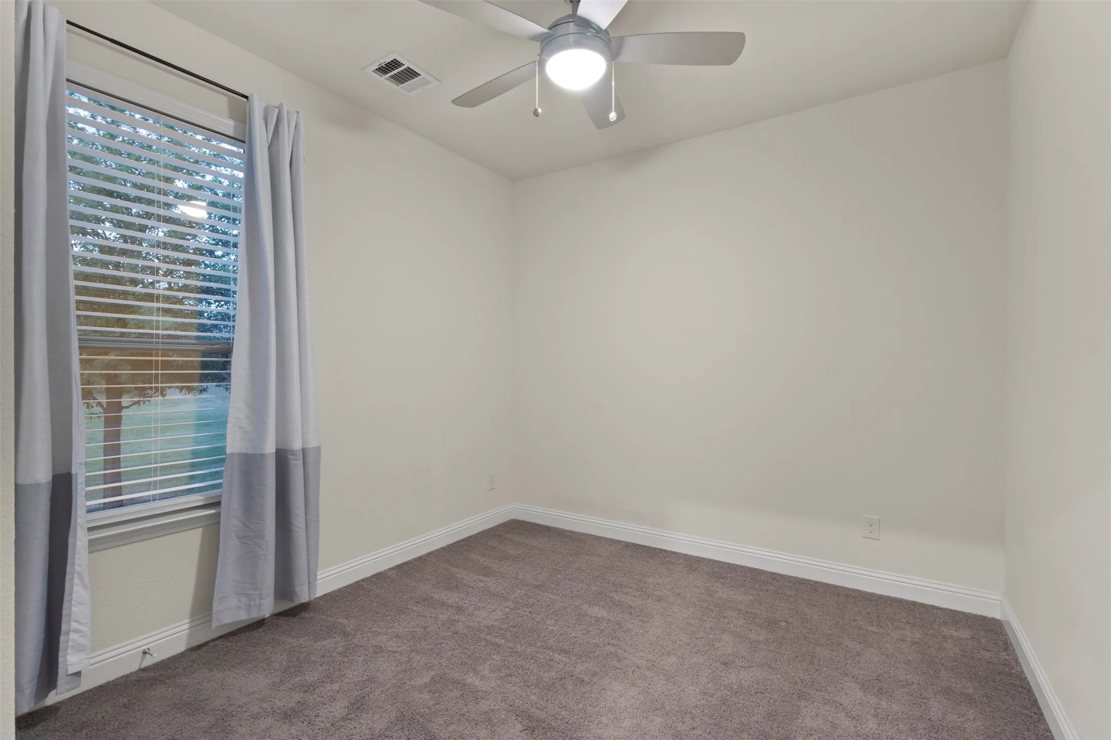 Window with blinds, wall-to-wall carpeting, ceiling fan with integrated lighting, and white baseboards