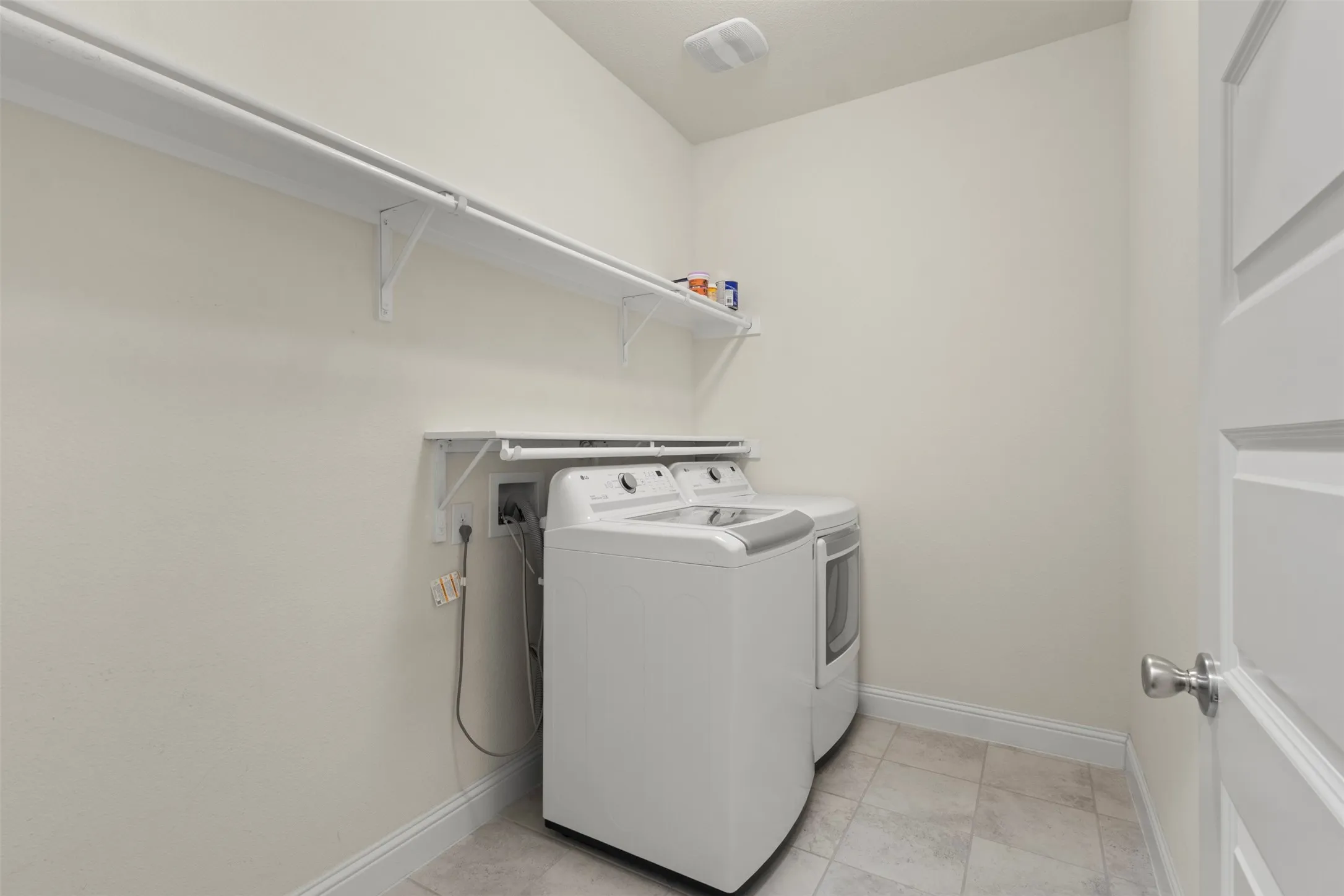 Laundry area with a built-in shelving system, tiled flooring, and a paneled door