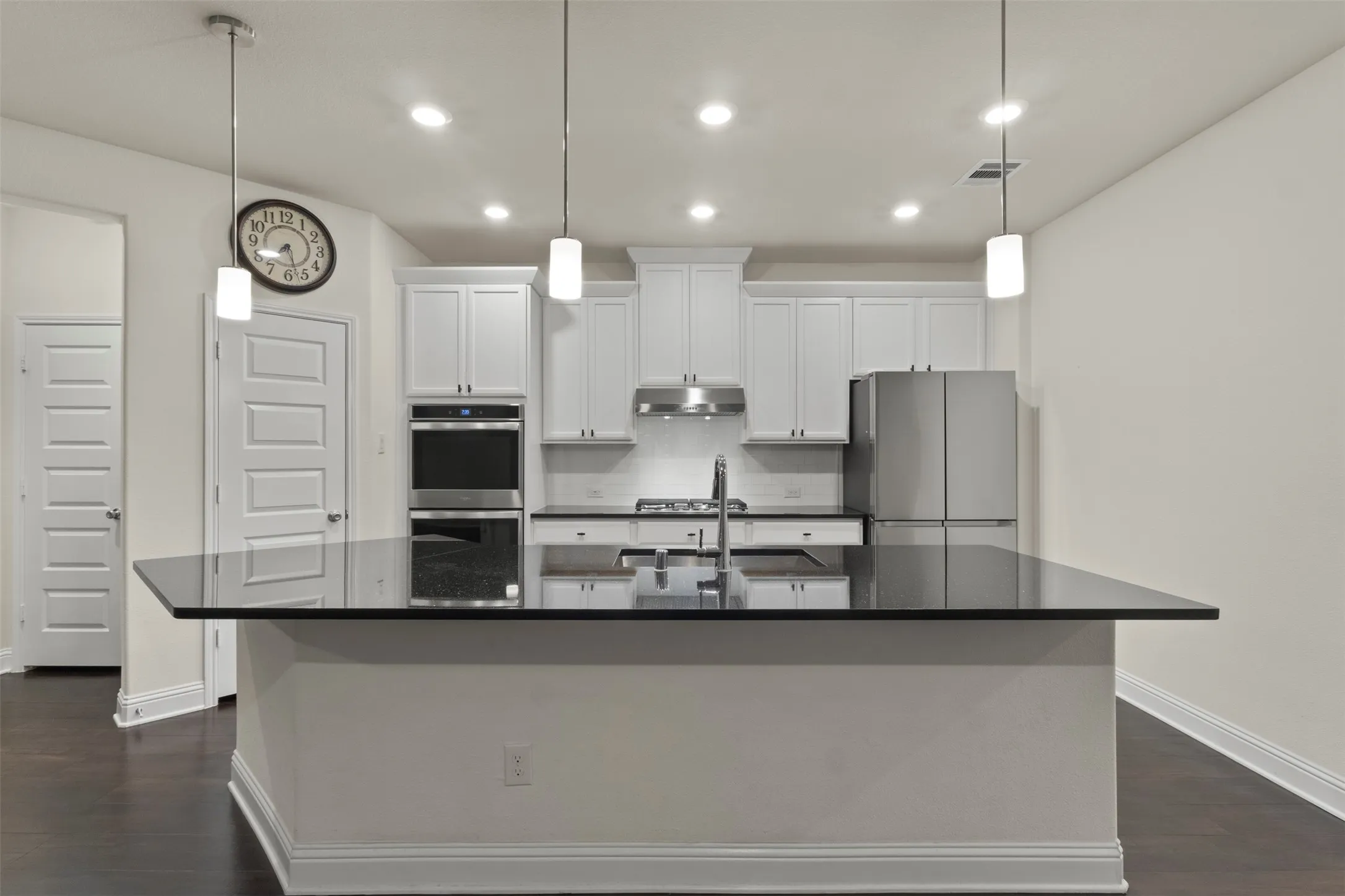 Kitchen featuring a center island with dark countertop, white shaker cabinetry, stainless steel appliances, and dark wood-finish flooring