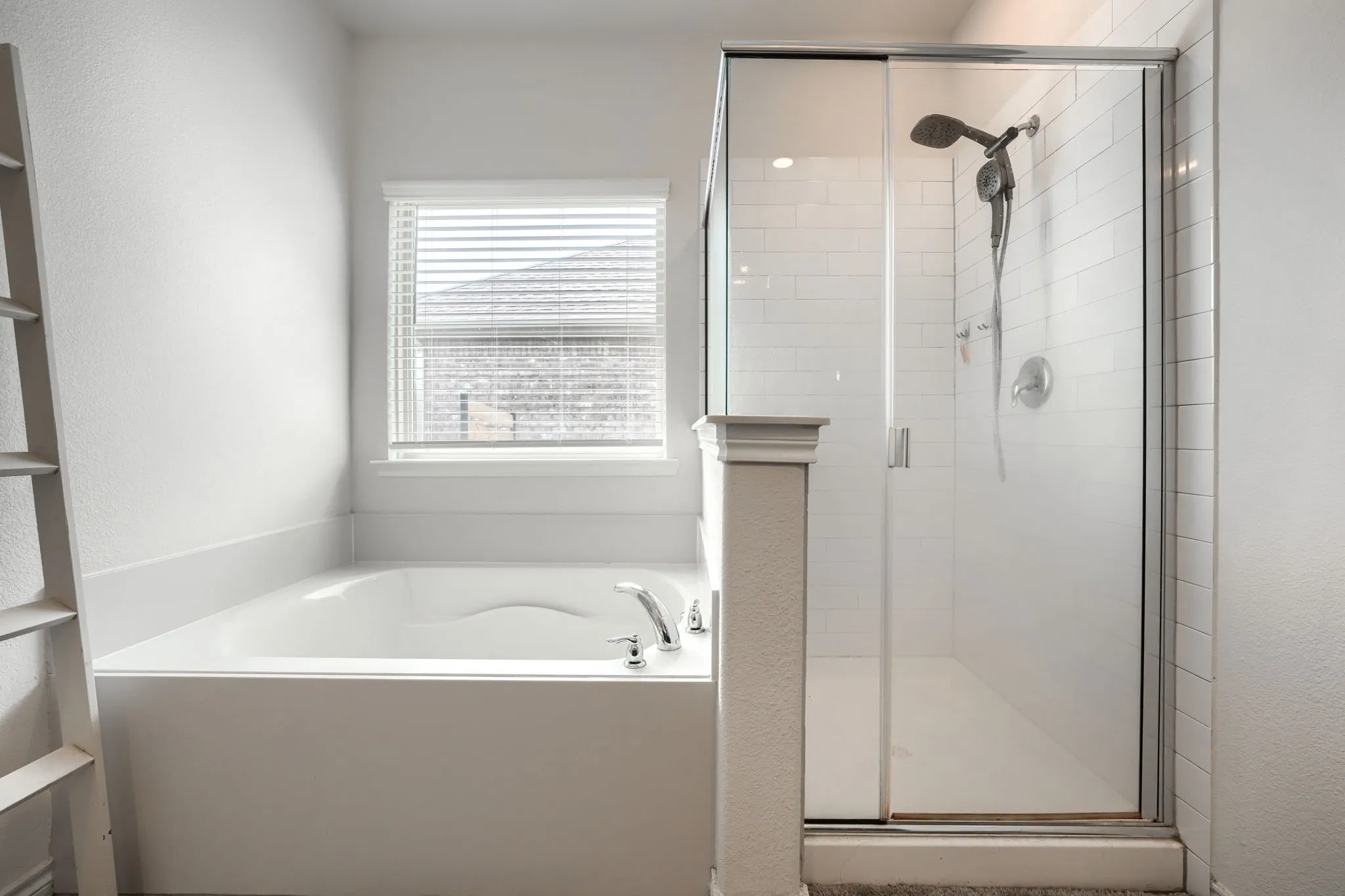 Built-in soaking tub with window, glass-enclosed shower with subway tile surround, and dual shower heads