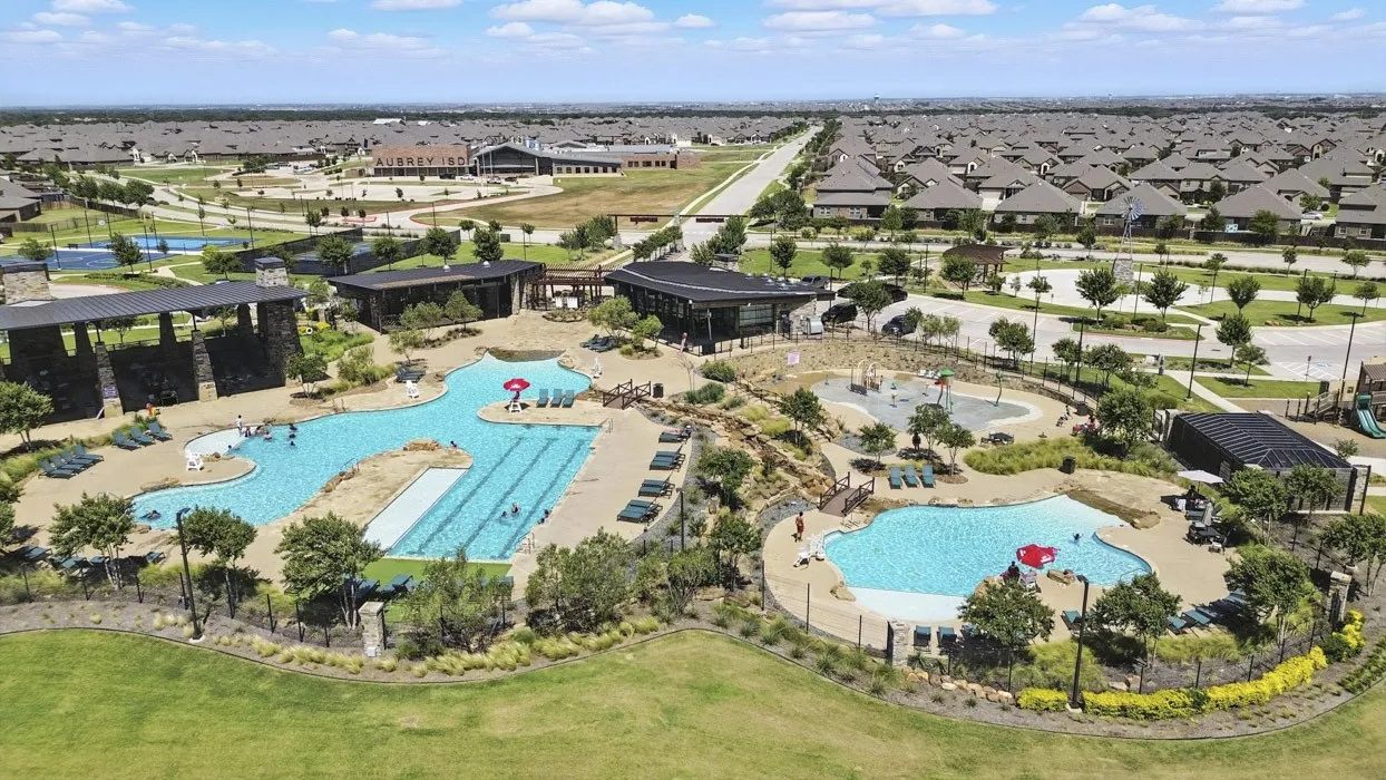 Community amenity center featuring multiple swimming pools, a lap pool, and extensive paved sun decks