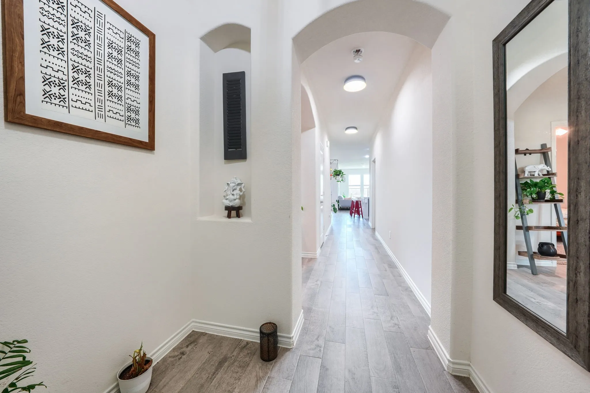 Hallway featuring recessed niche, arched doorways, wood-finish flooring, and recessed ceiling lighting
