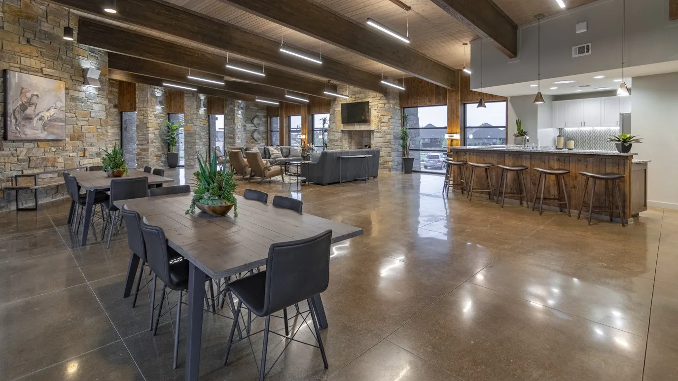 Exposed wood beams, polished concrete flooring, stone accent walls, recessed lighting, and a kitchen island with seating
