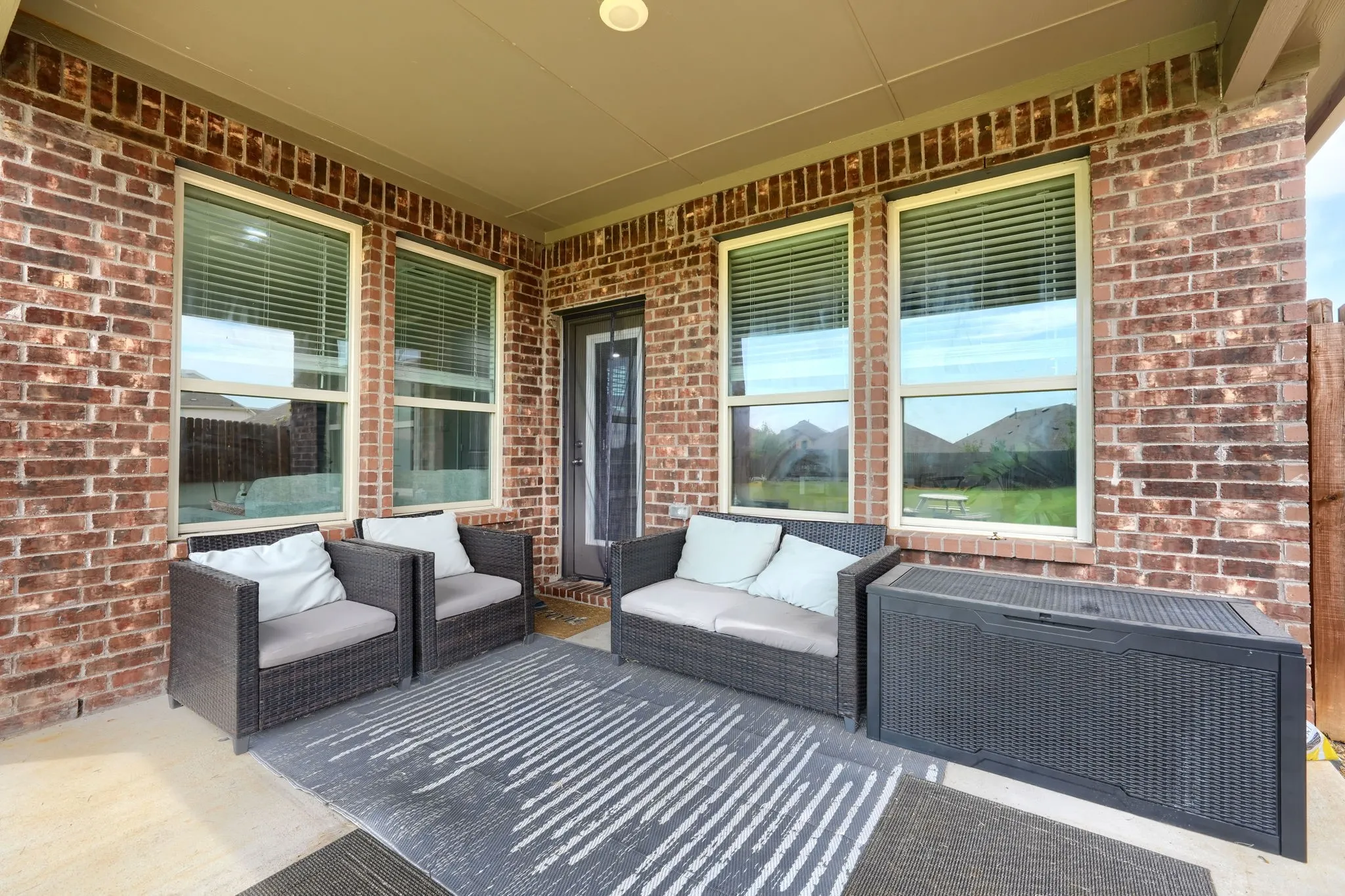 Covered patio featuring a brick exterior and multiple windows
