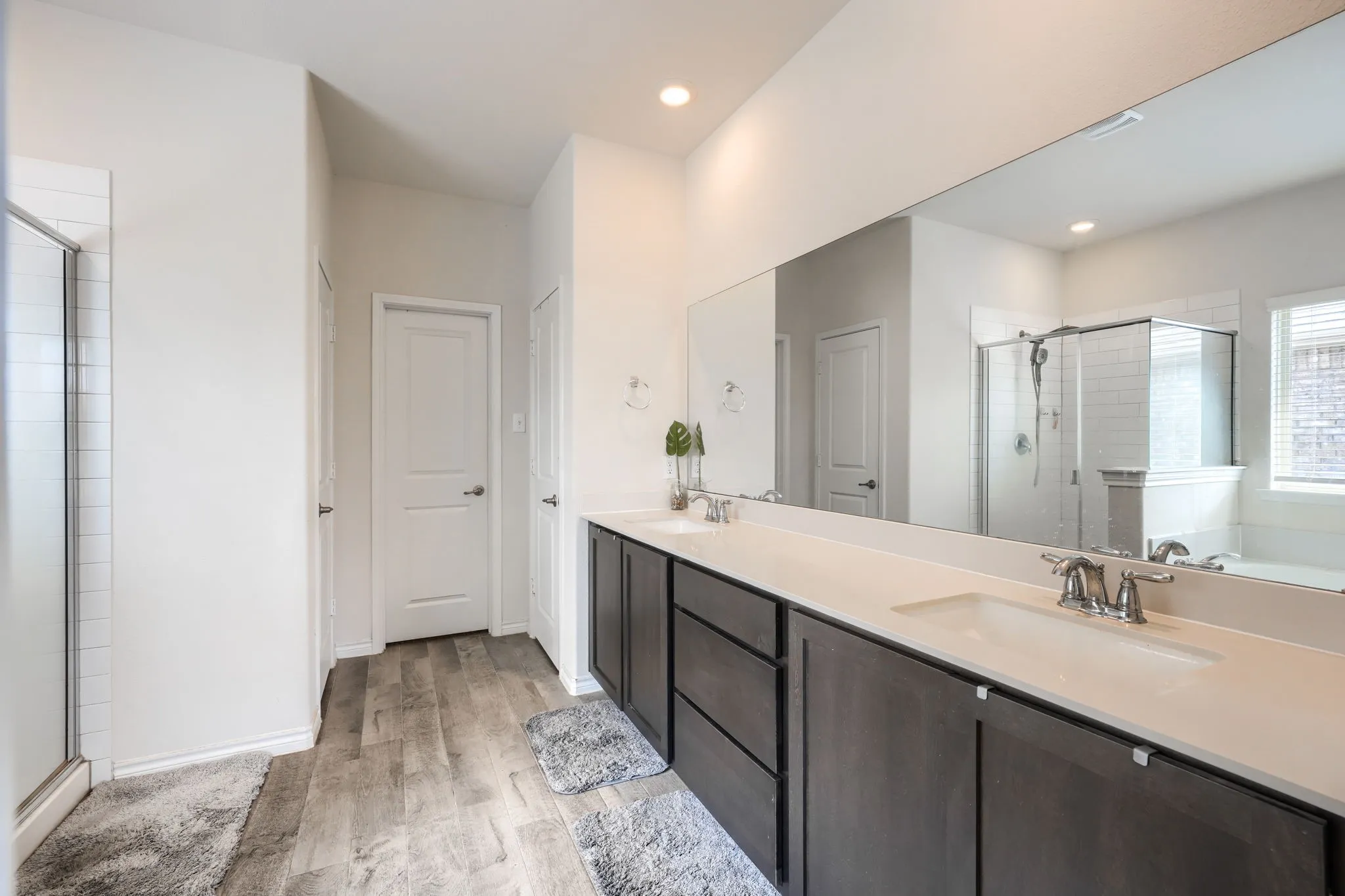 Dual vanity with white undermount sinks, wood-finish cabinetry, and a full-width mirror
