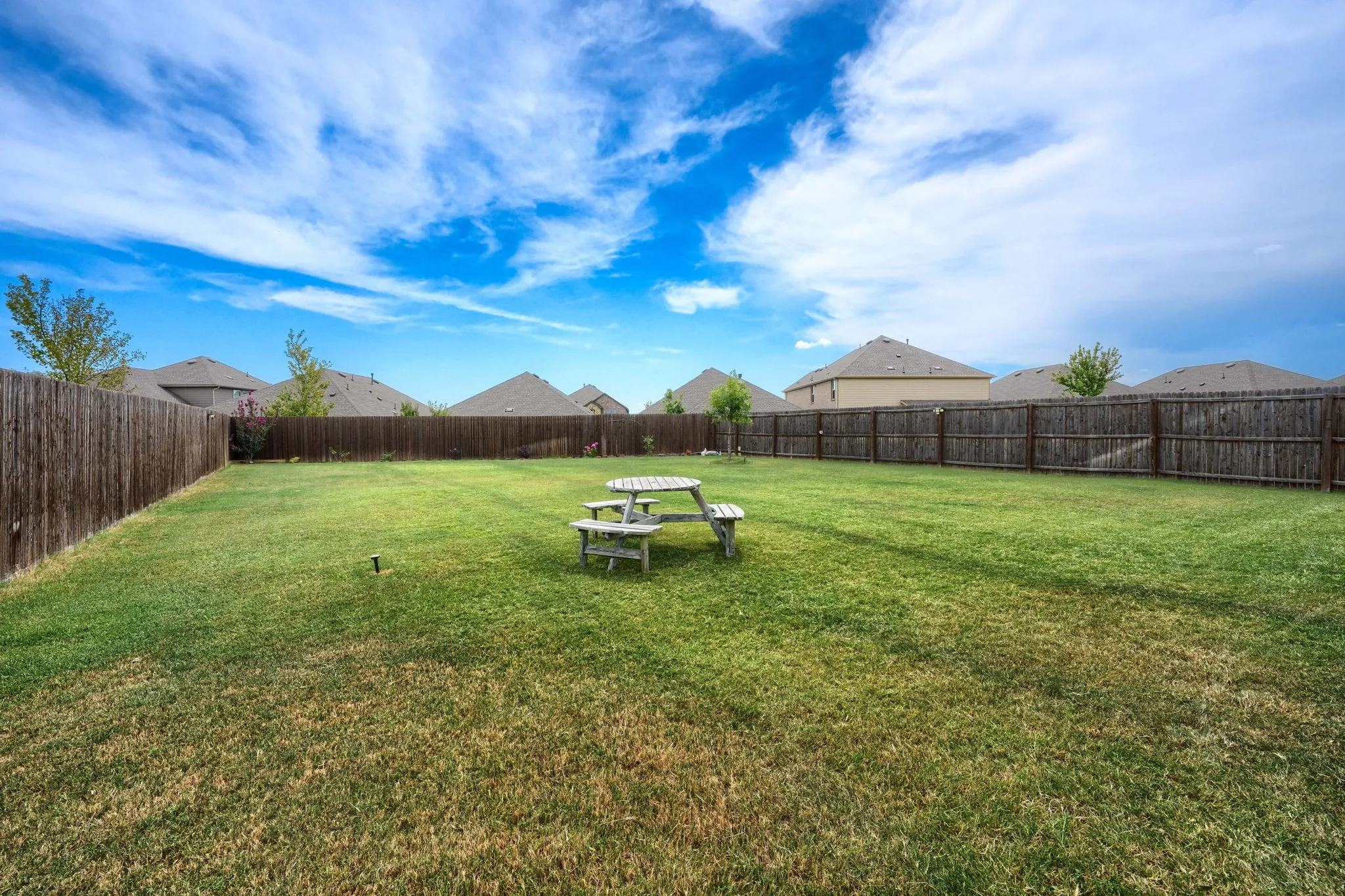 Expansive fenced backyard featuring a substantial lawn