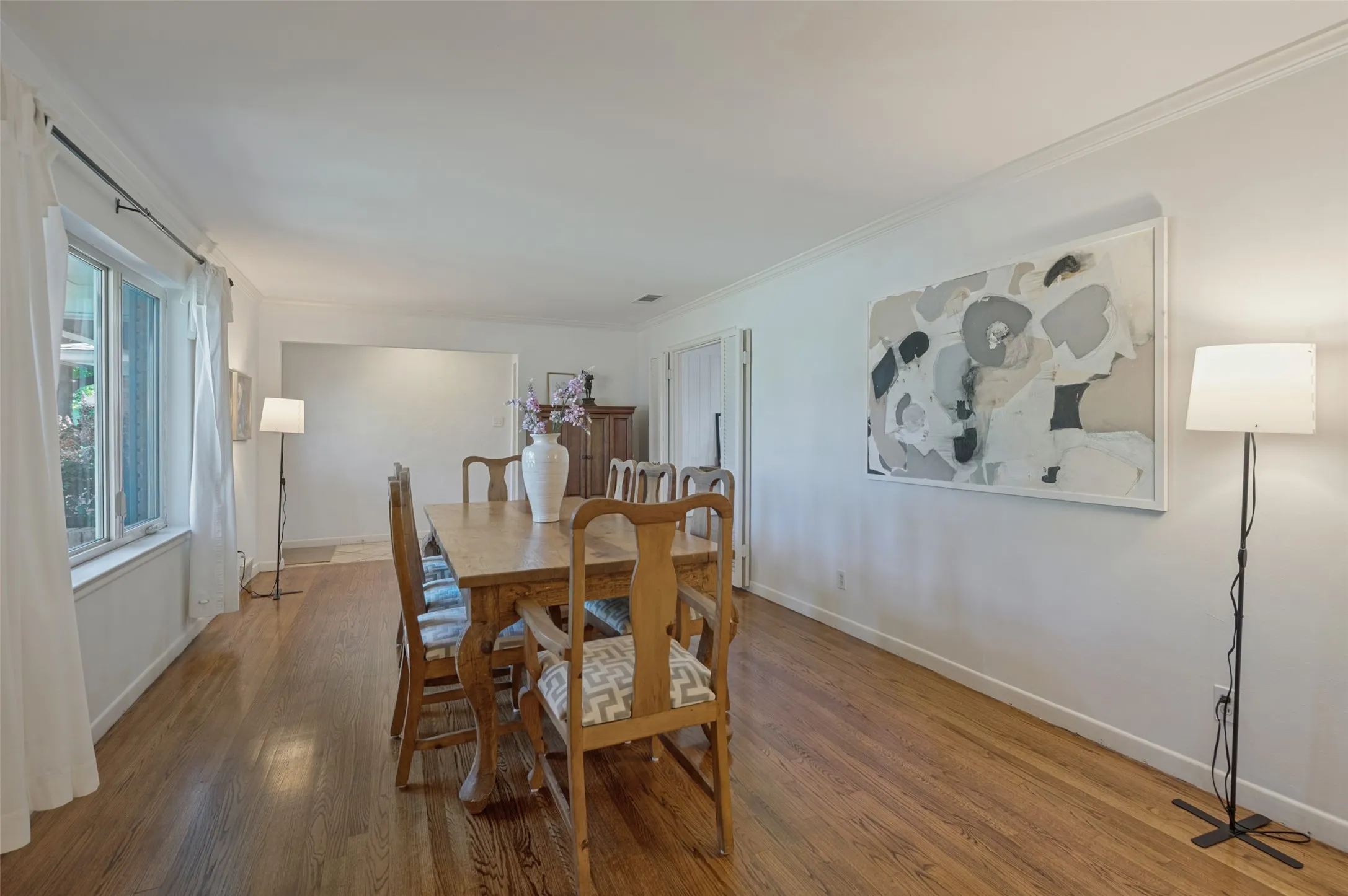 Hardwood flooring throughout, white walls, crown molding, and large windows with white trim