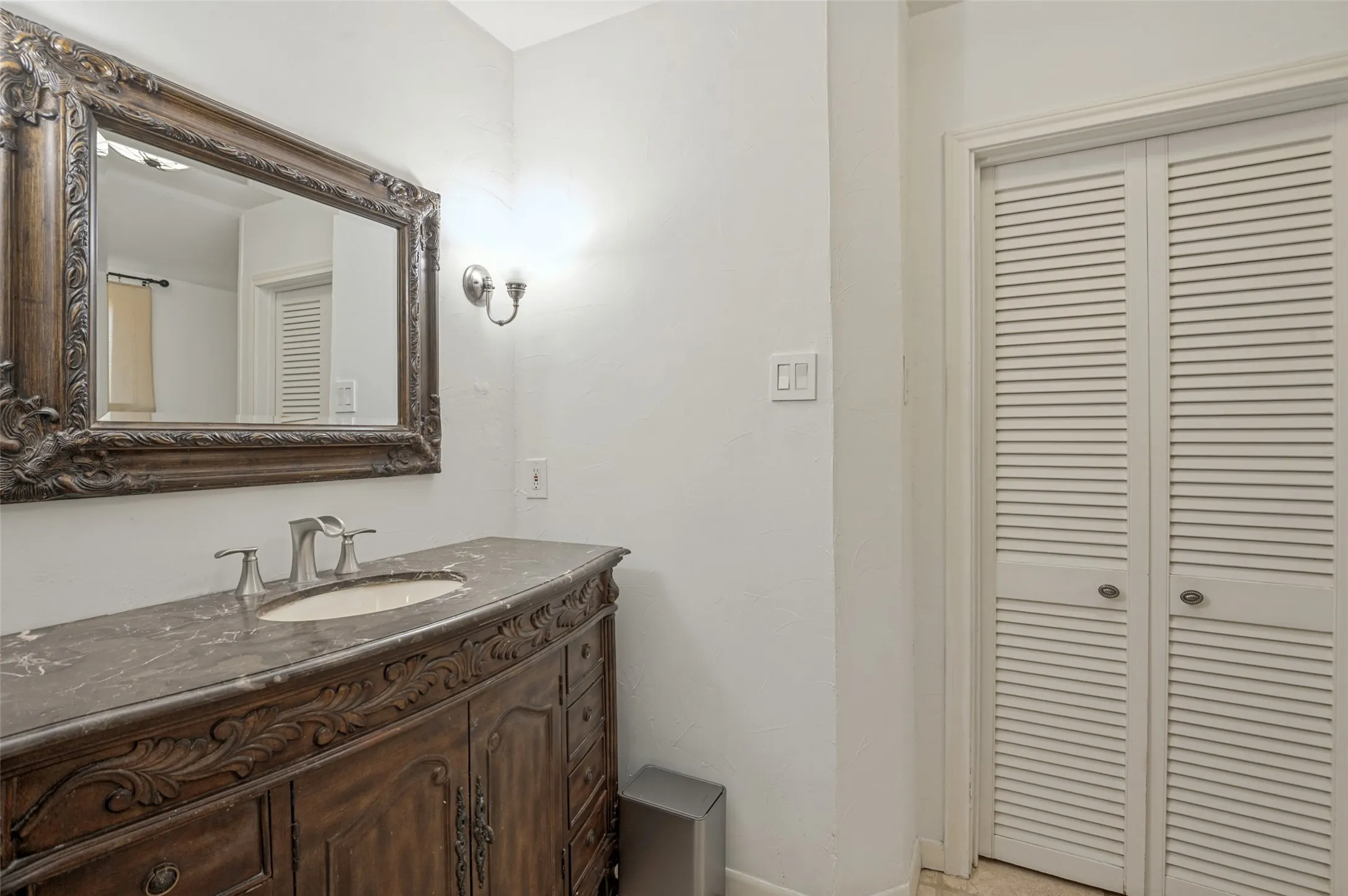Ornate wood-finish vanity with a stone countertop and undermount sink