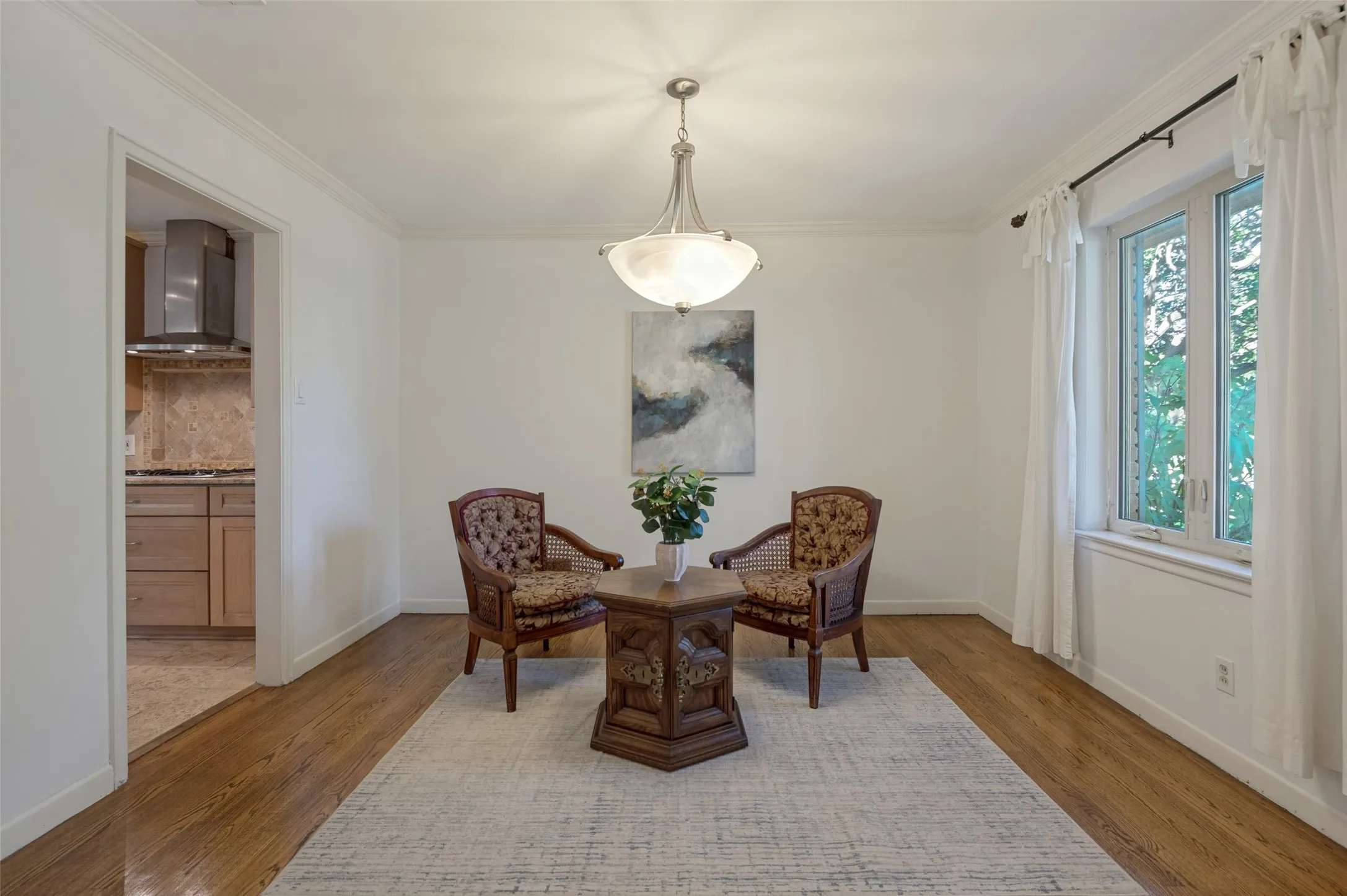 Wood-finish flooring throughout, crown molding details, and a multi-pane window