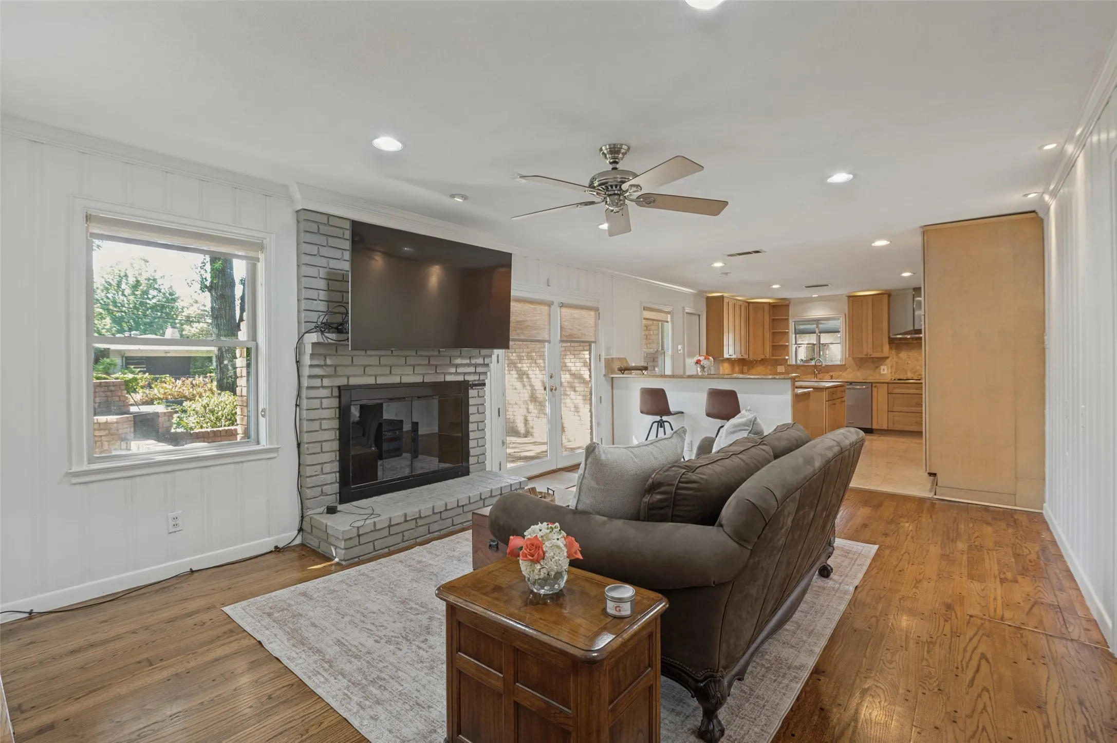 Living area featuring wood-finish flooring, a painted brick fireplace, and recessed lighting