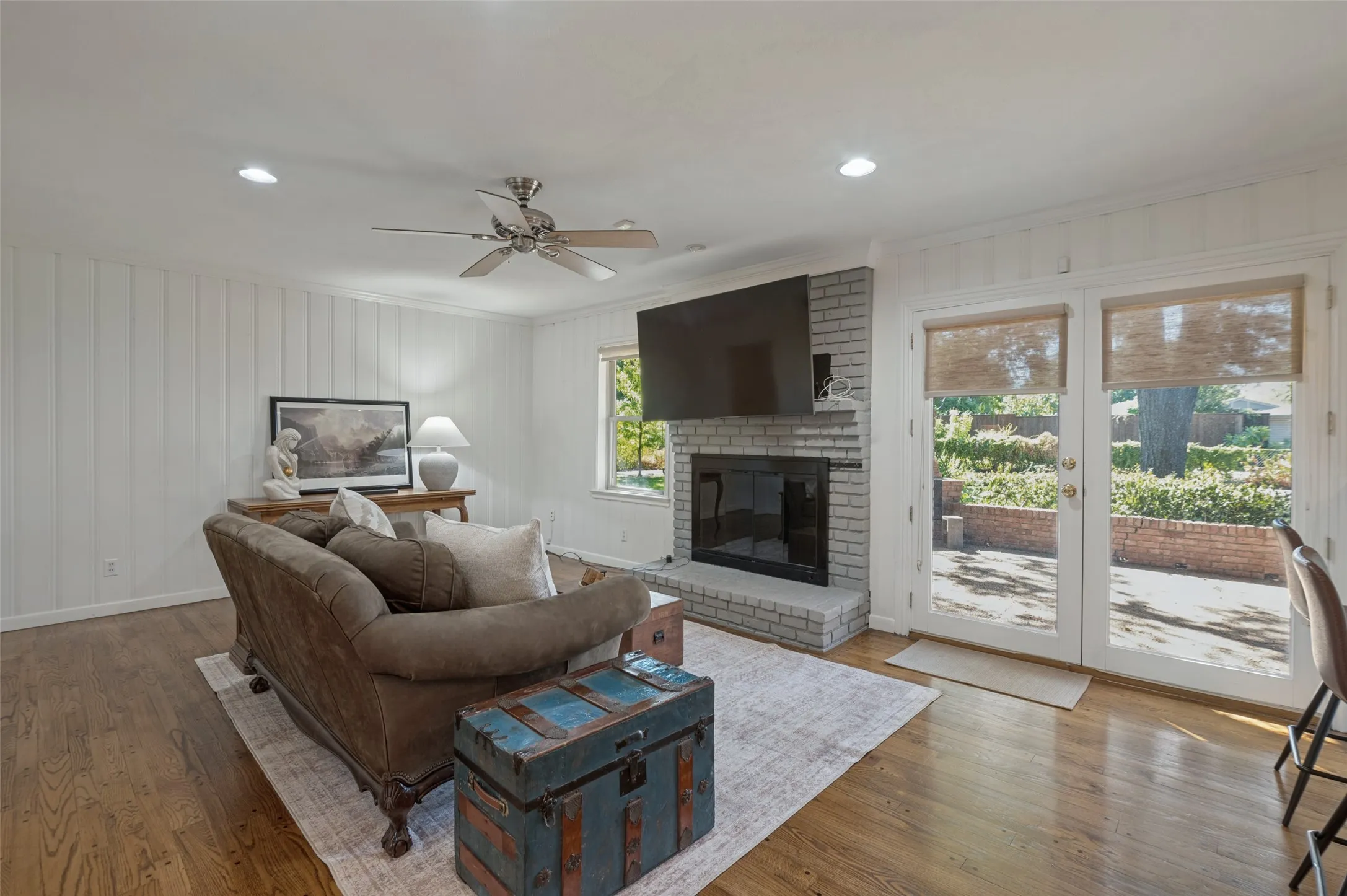 Shiplap accent walls, wood-finish flooring, and a brick fireplace with a hearth