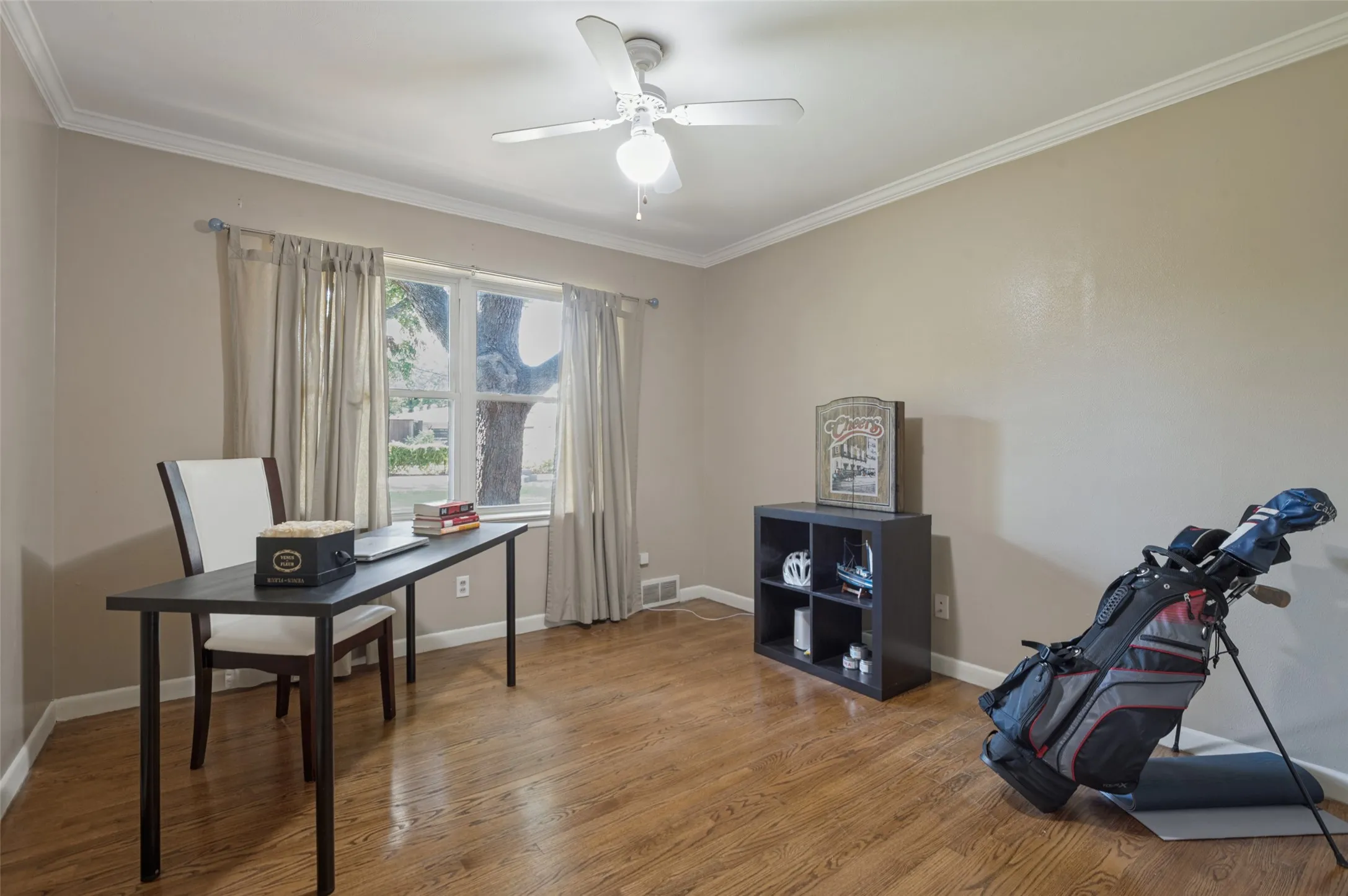 Hardwood-finish flooring, crown molding, ceiling fan with integrated lighting, and a large window