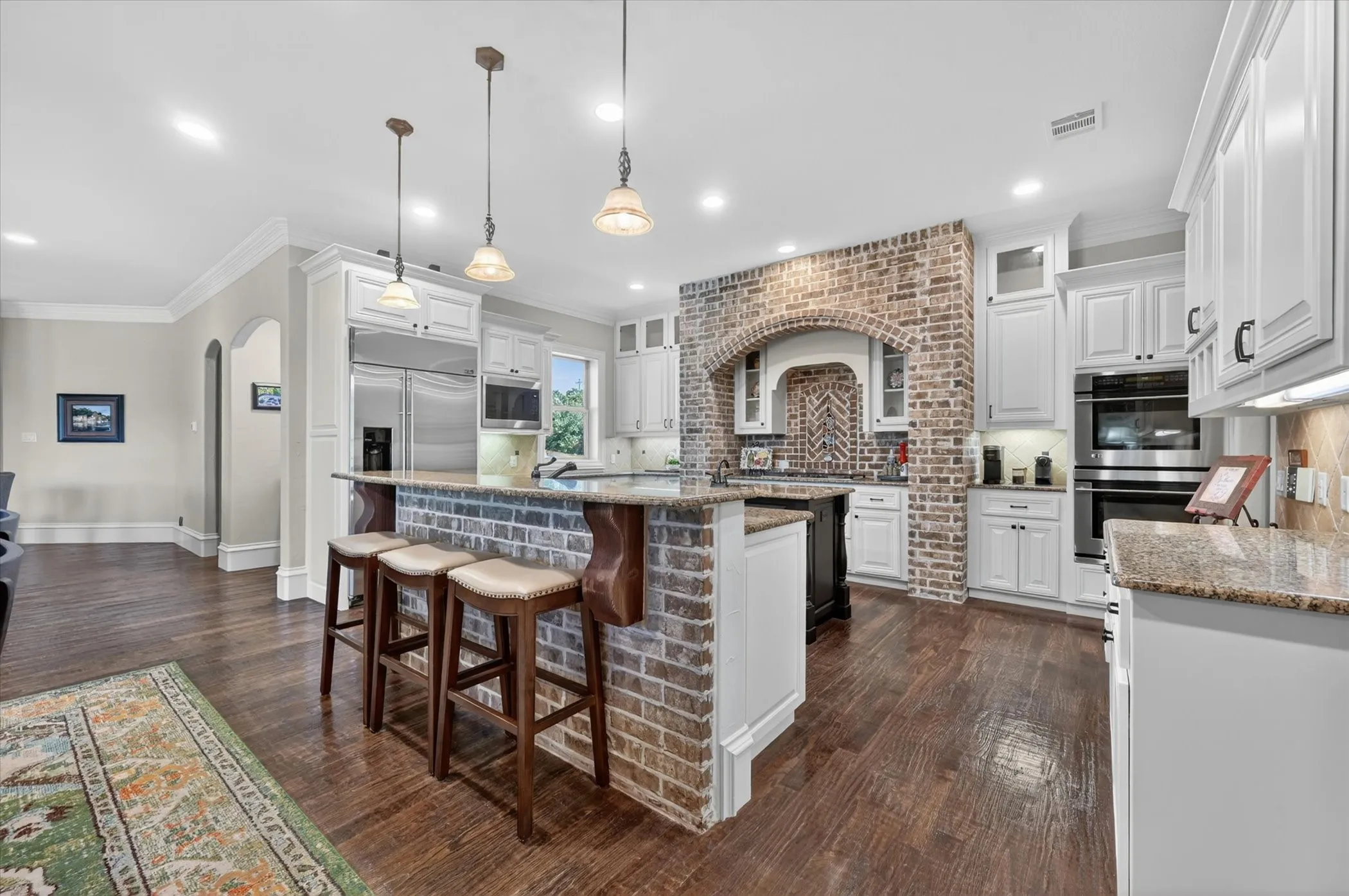 Host in the gourmet kitchen featuring high-end appliances, a gas cooktop, center island with a prep sink, bar seating, walk-in pantry, butler’s pantry & a wine room with an Avanti fridge & space for nearly 200 bottles.