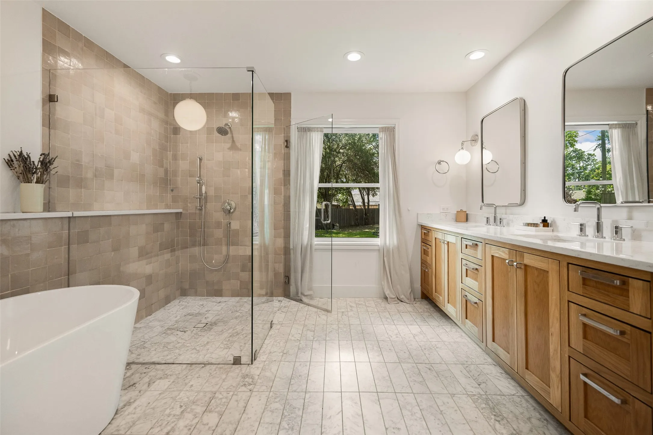 stunning and spacious primary bathroom retreat featuring marble tile, with dual vanities, walk in shower, soaking tub.
