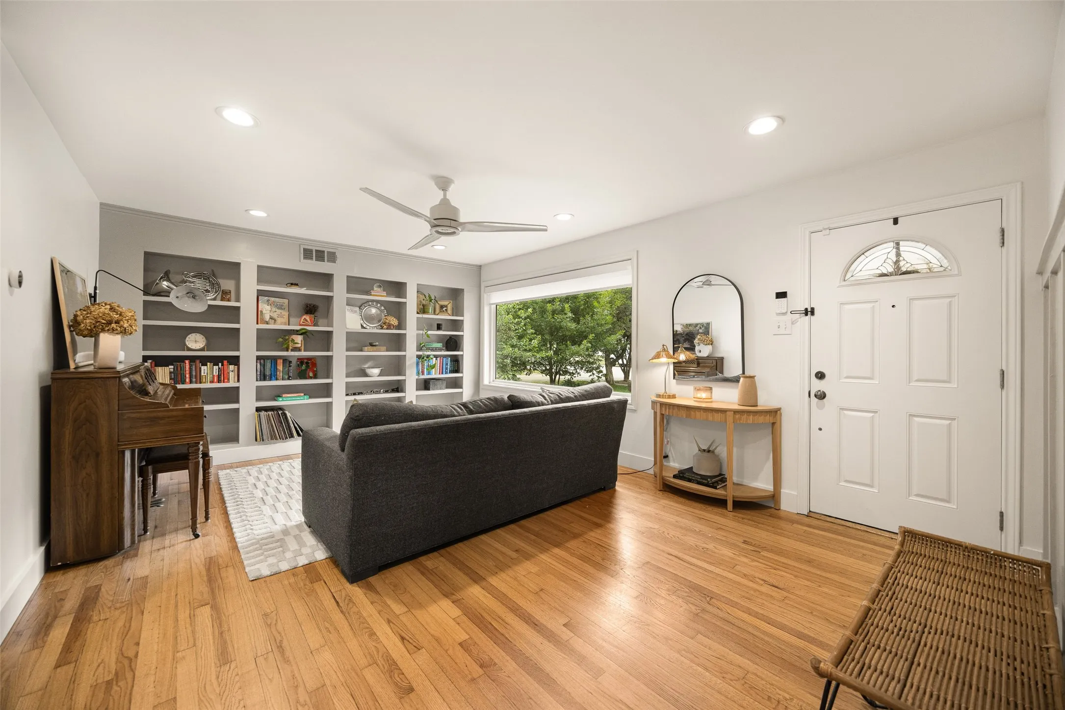 second living area awash with natural light, thanks to a large picture window, featuring custom built ins