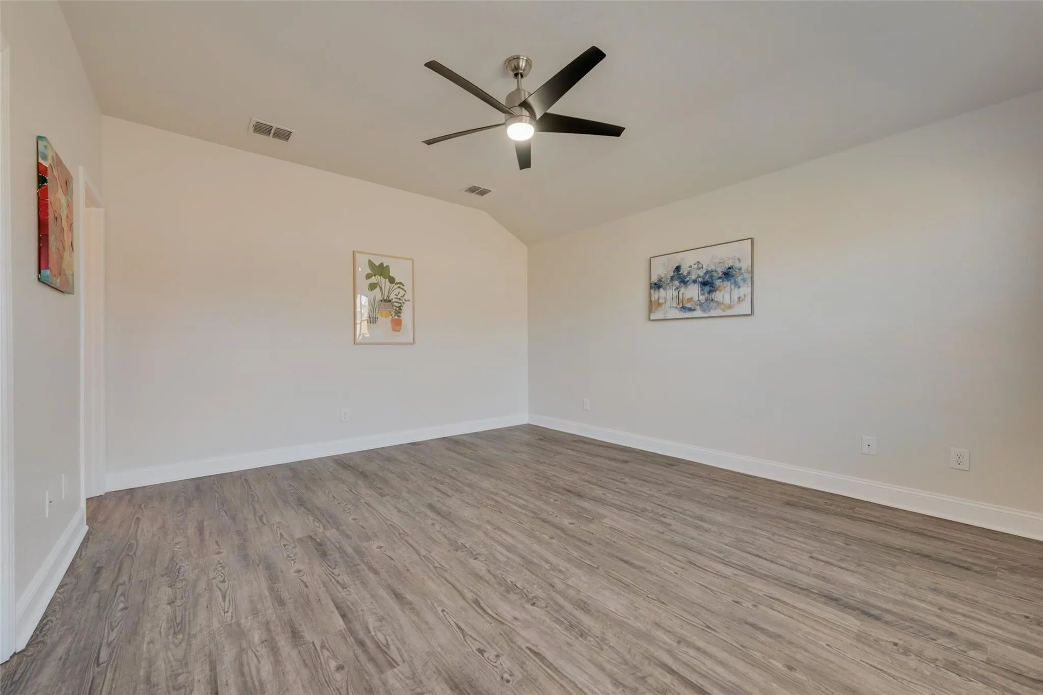 Vaulted ceiling with a contemporary ceiling fan, light wood-finish flooring, and white baseboards