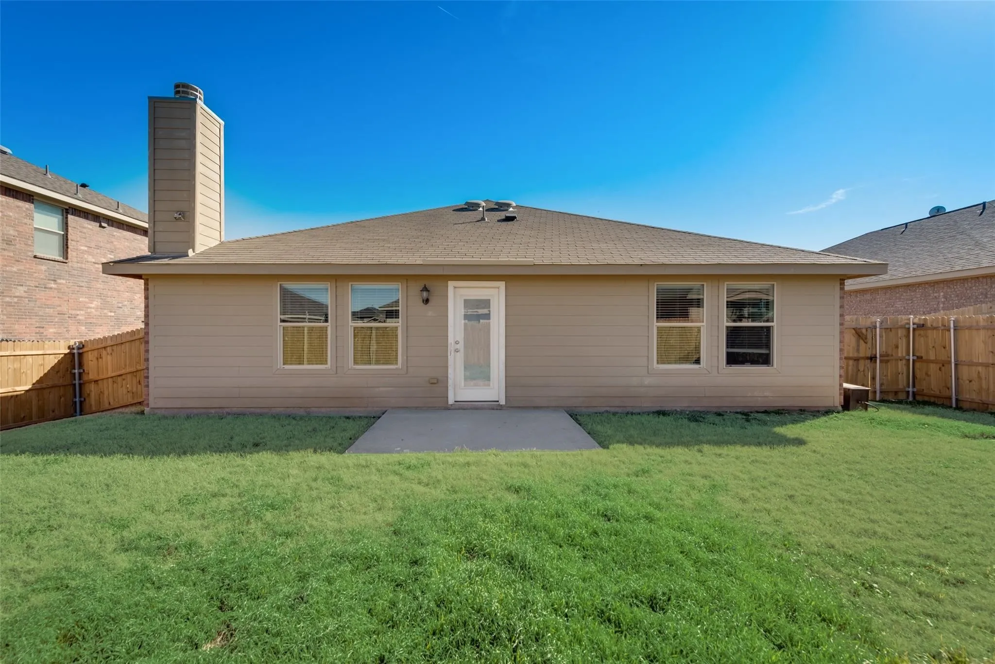 Rear exterior featuring a concrete patio, a chimney, and a durable shingle roof