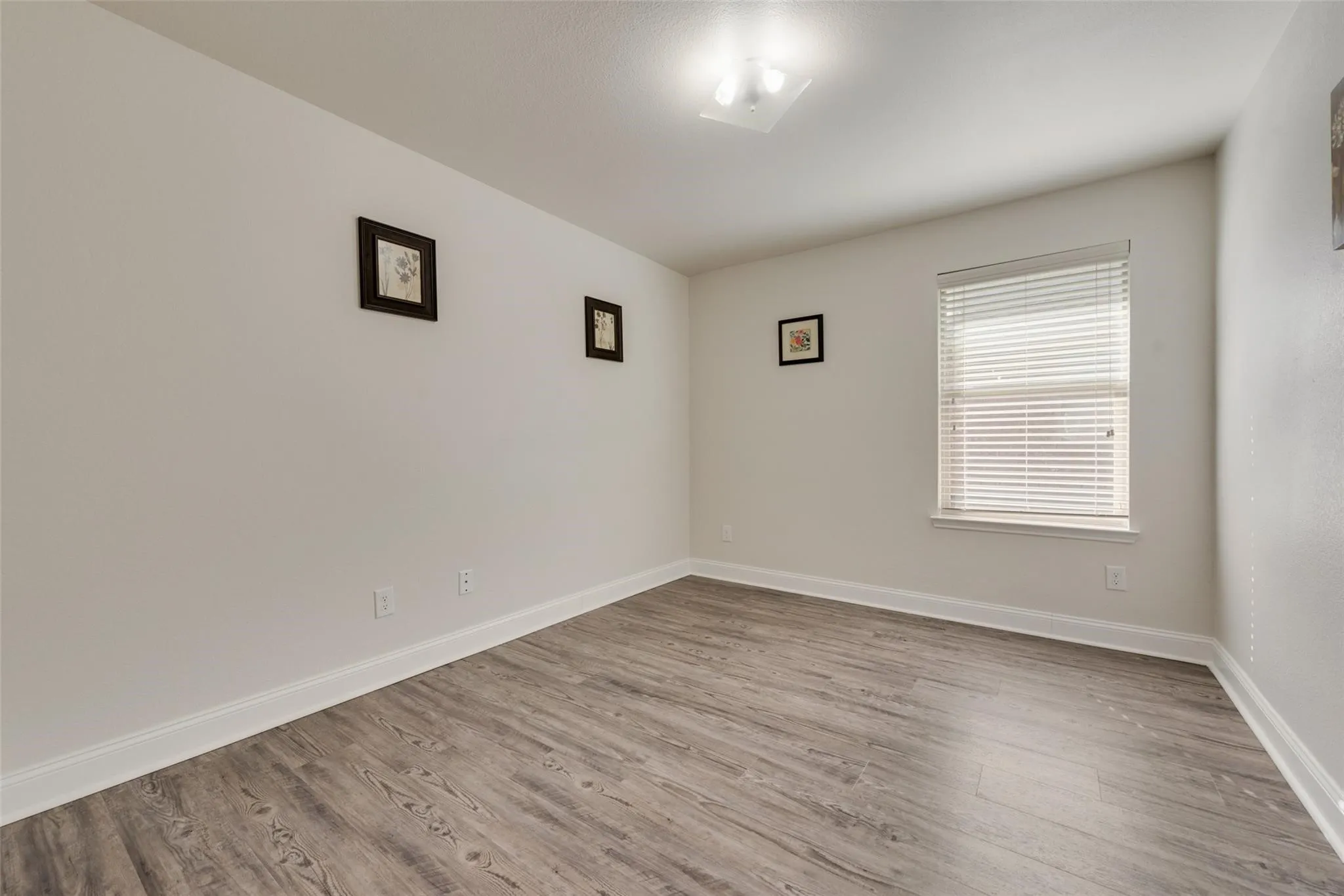 Room featuring wood-finish flooring, a single window with blinds, and flush-mount ceiling lighting