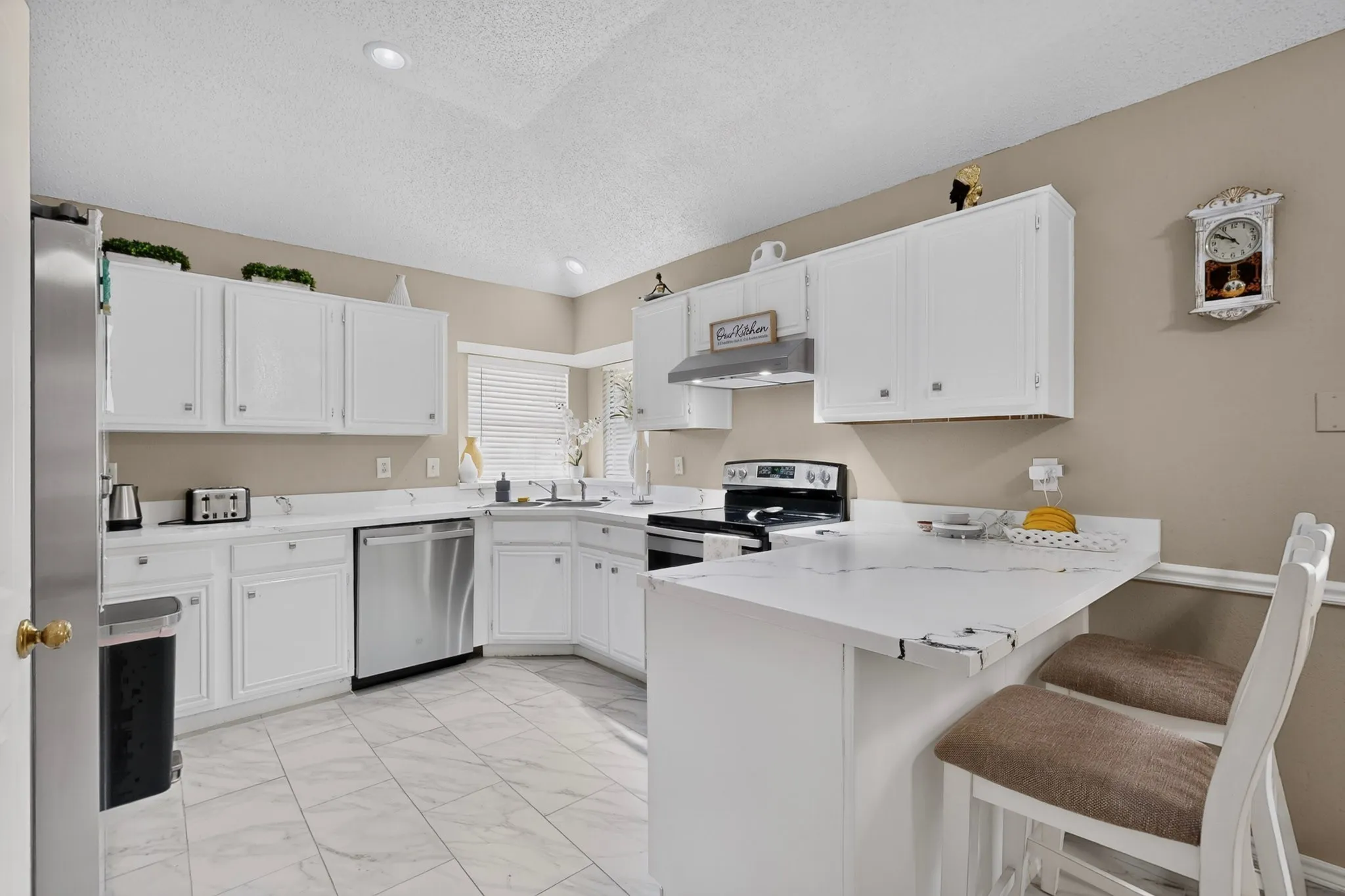 Kitchen featuring white cabinetry, white countertops, stainless steel appliances, a corner sink, and recessed lighting