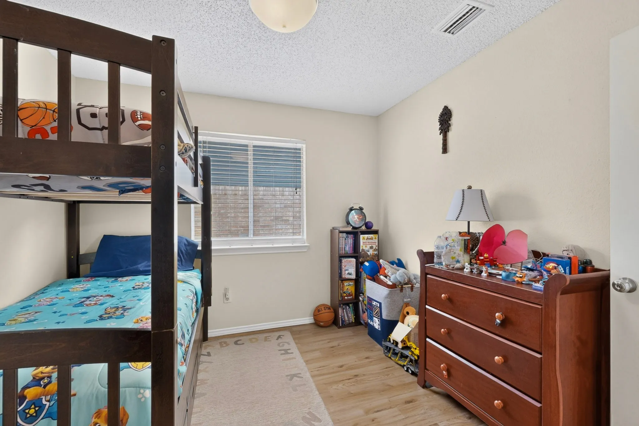 Wood-finish flooring, a single window with blinds, and light-toned walls