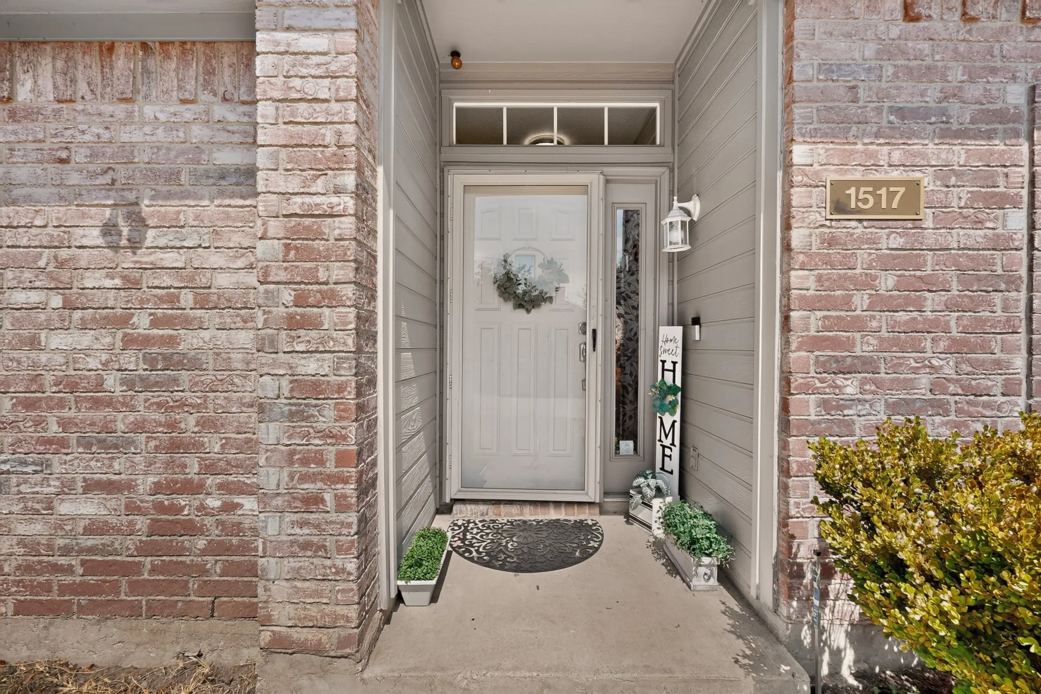 Brick and siding exterior featuring an entryway with a transom window, sidelight, and an exterior wall light