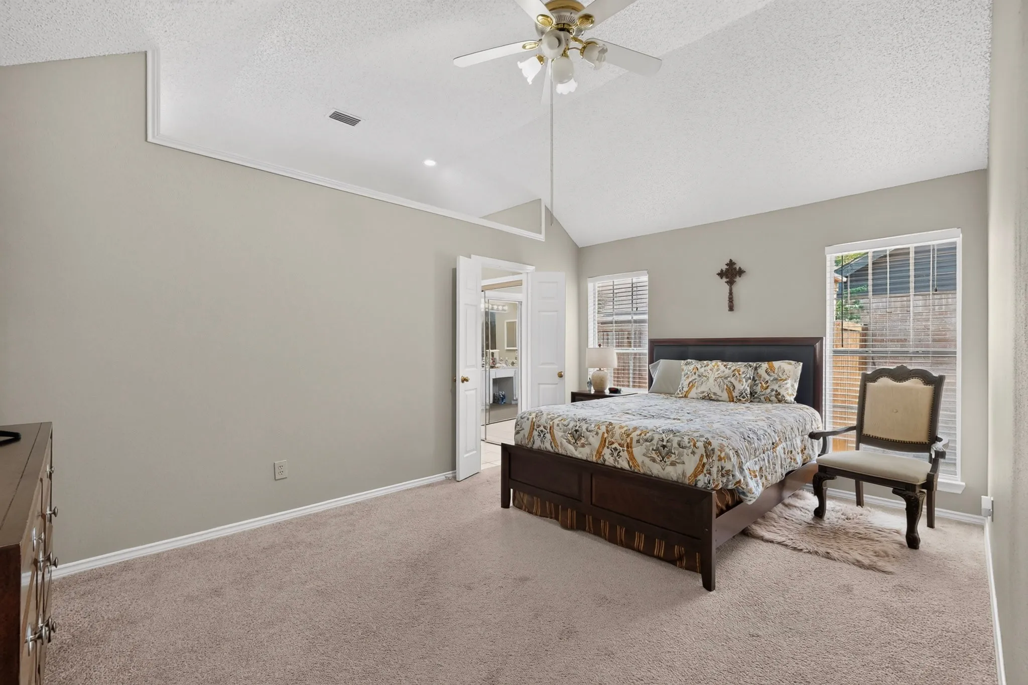 Vaulted ceiling with a ceiling fan, dual windows with horizontal blinds, and neutral carpeting