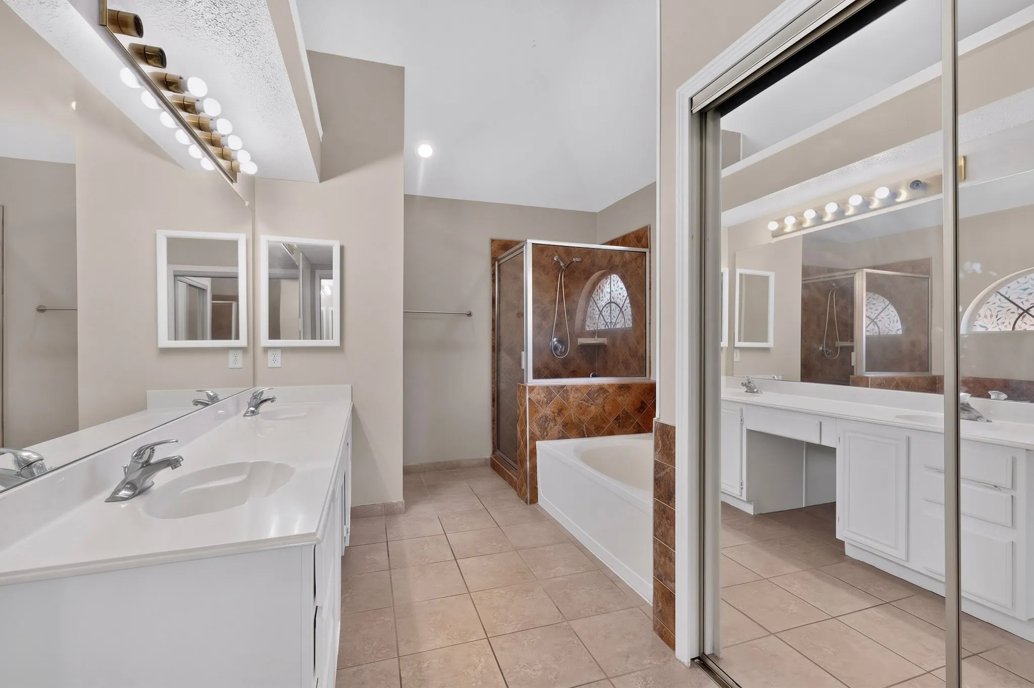 Dual vanity with expansive countertop, built-in bathtub, glass-enclosed shower, and tiled flooring