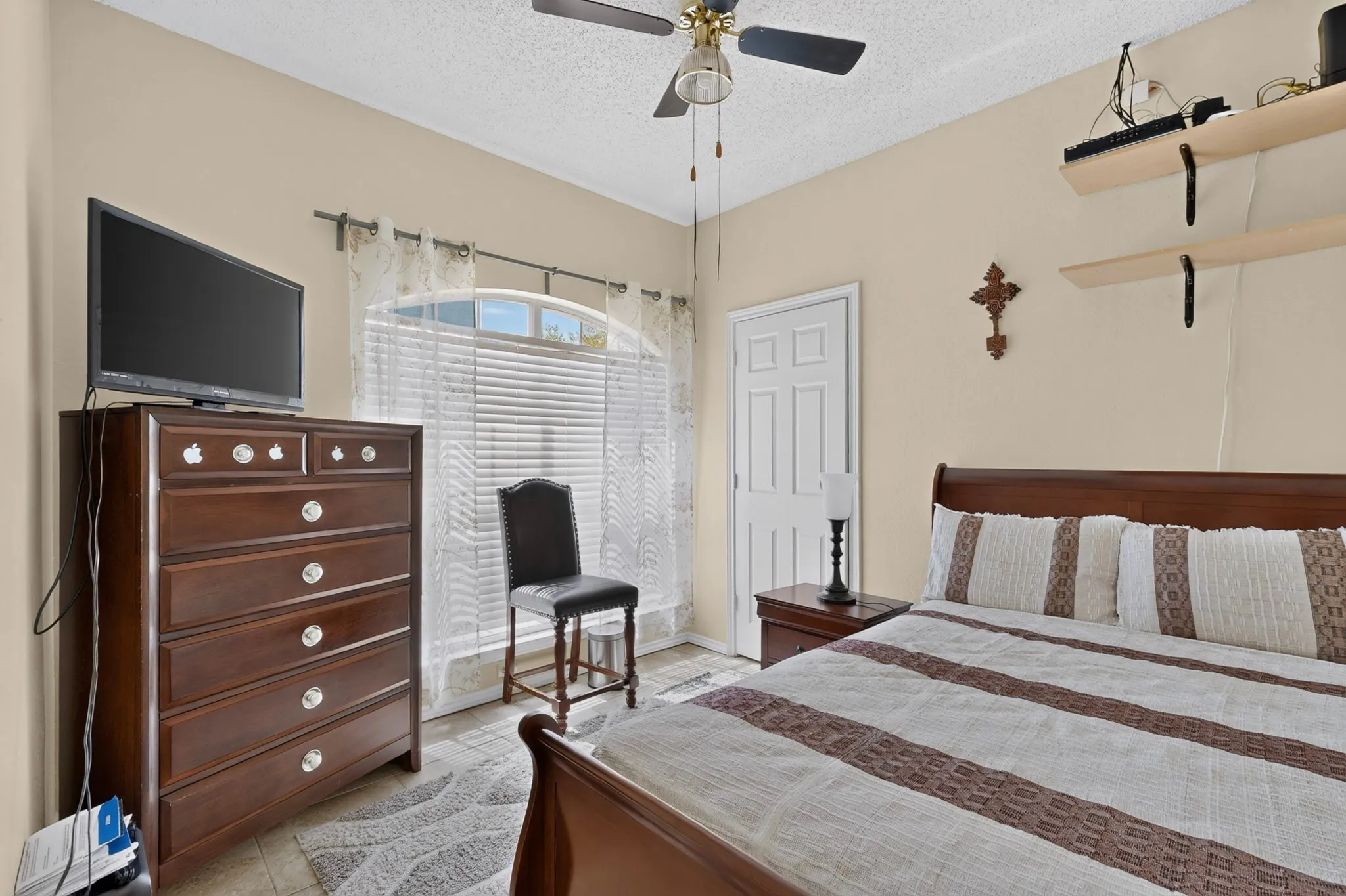 Arched window with blinds, ceiling fan, and light-toned walls