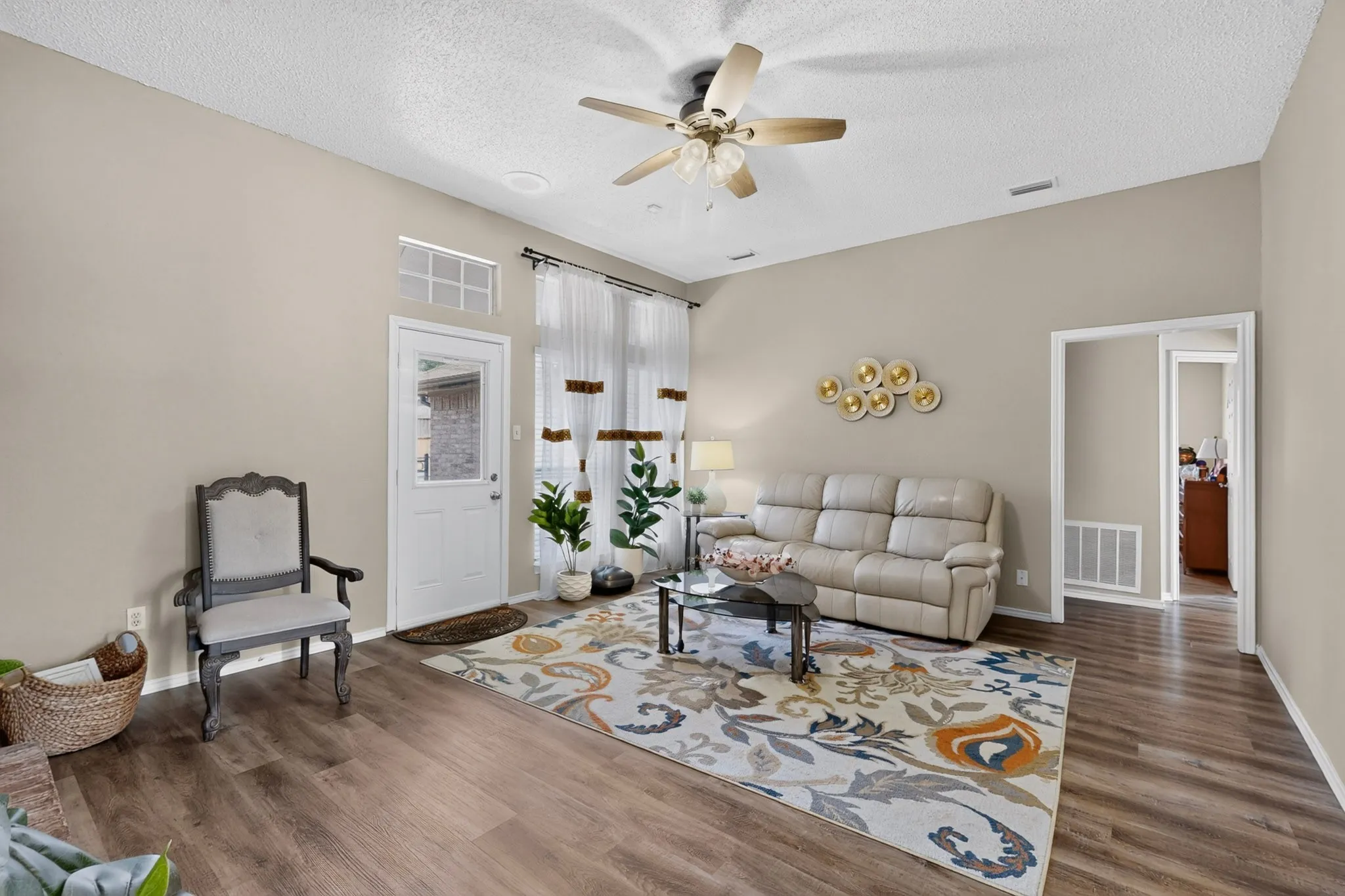 Vaulted ceiling with a ceiling fan, wood-finish flooring, and a transom window above the exterior door