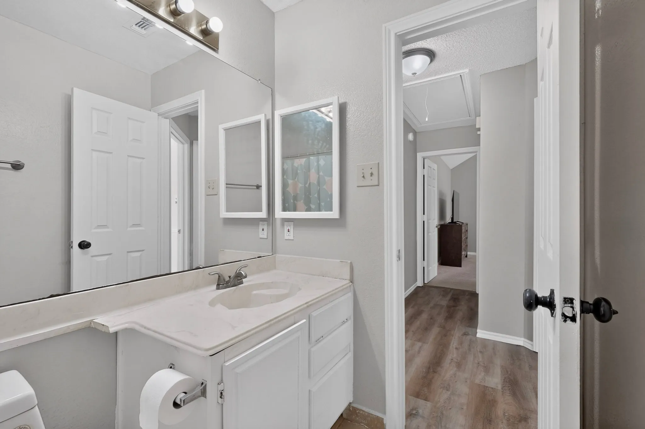 Vanity with integrated sink, wall-mounted light fixture, and mirror