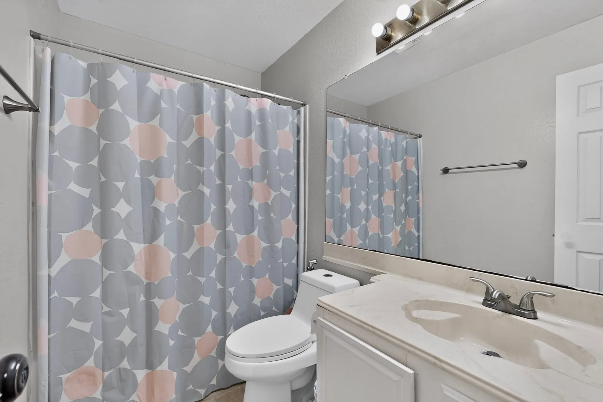 Vanity with integrated sink, chrome faucet, and expansive wall-mounted mirror