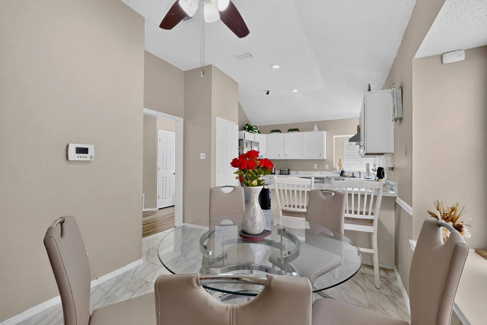 Vaulted ceiling with a ceiling fan, white cabinetry, light-toned wall paint, and tile flooring