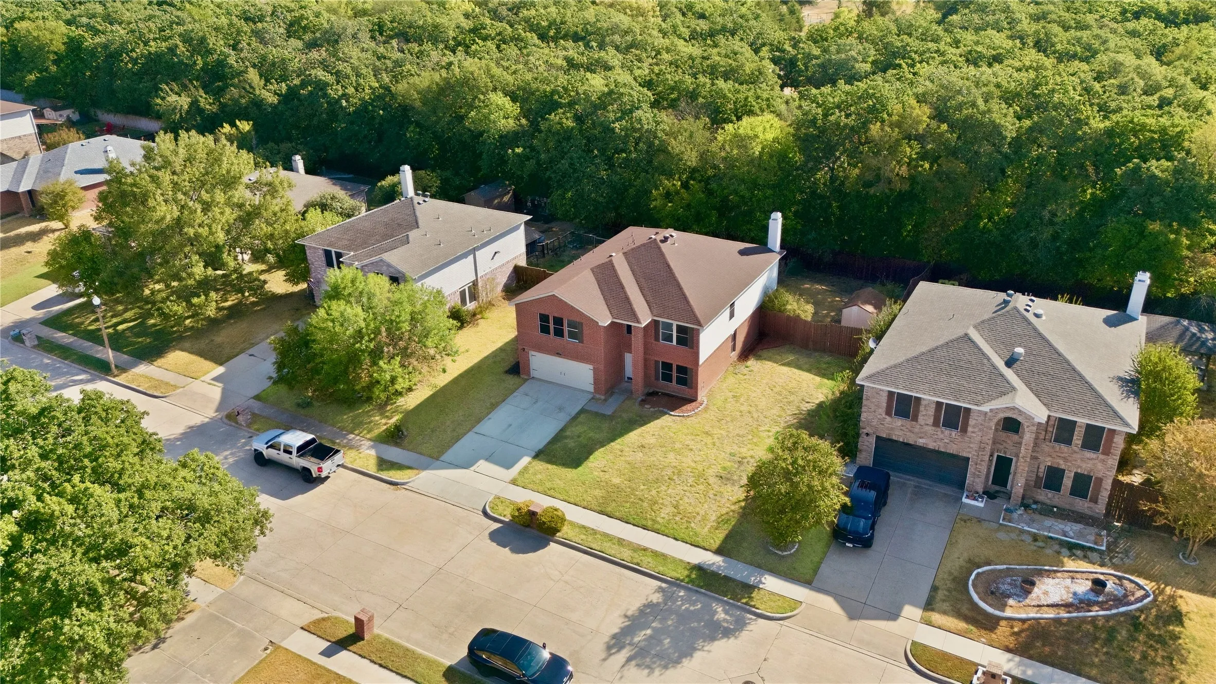 Traditional brick-front residence with a two-car garage, concrete driveway, and mature landscaping