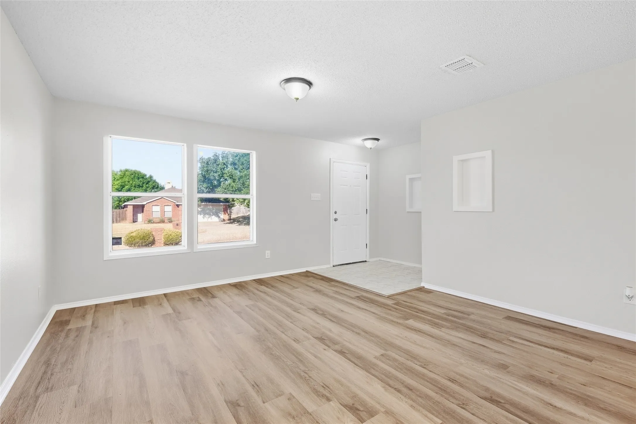 Wood-finish flooring throughout the main living area, complemented by white walls and trim