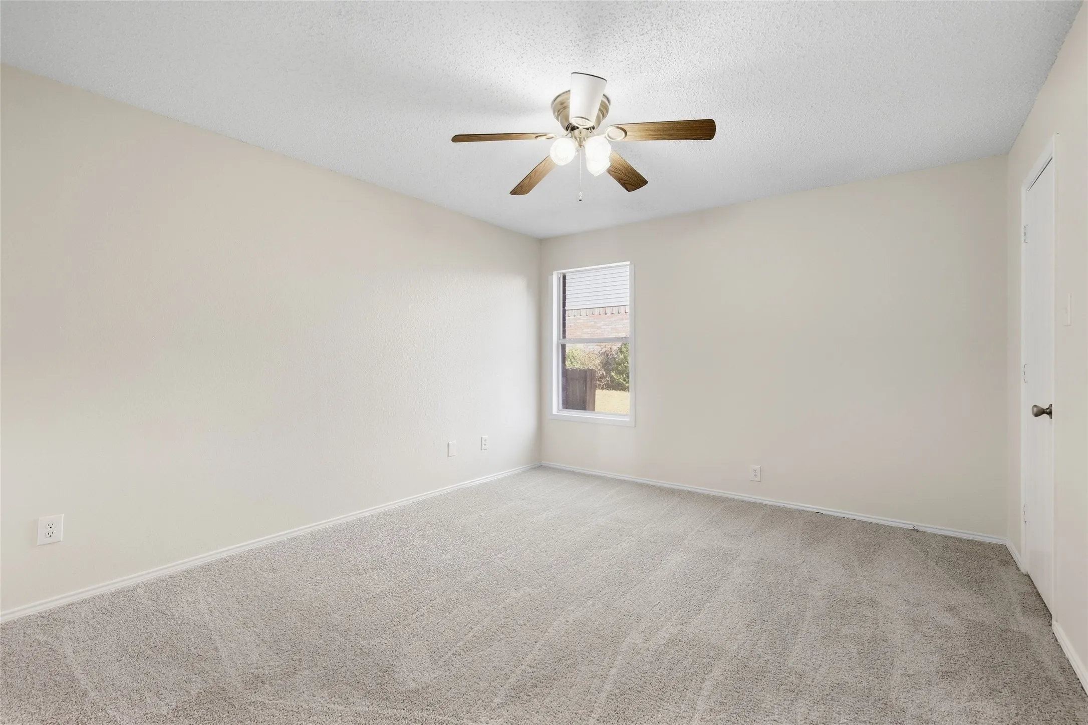 Wall-to-wall carpeting, window with blinds, ceiling fan with light fixture, and a solid door