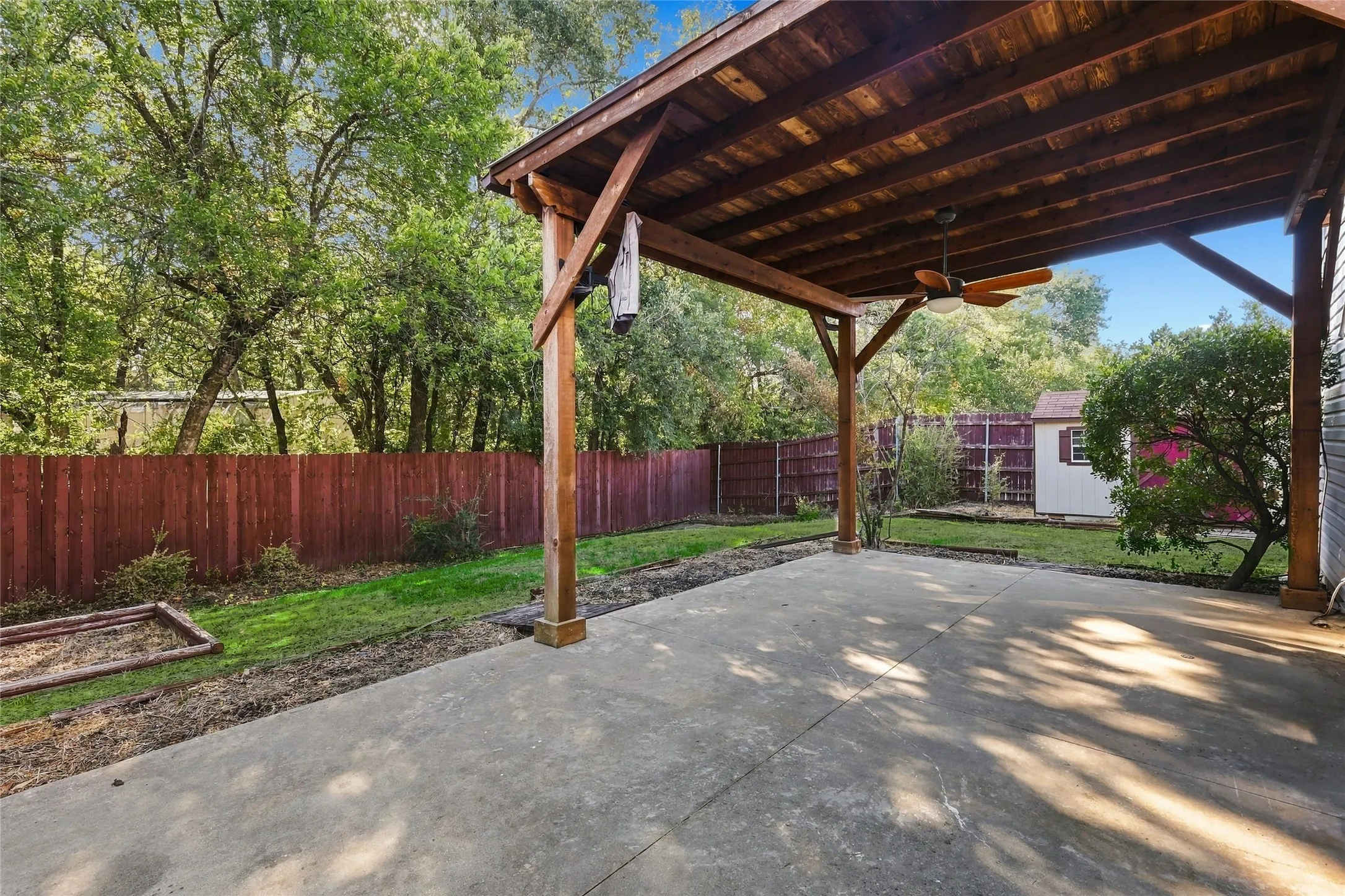 Covered patio featuring a wood-plank ceiling, ceiling fan, and concrete flooring