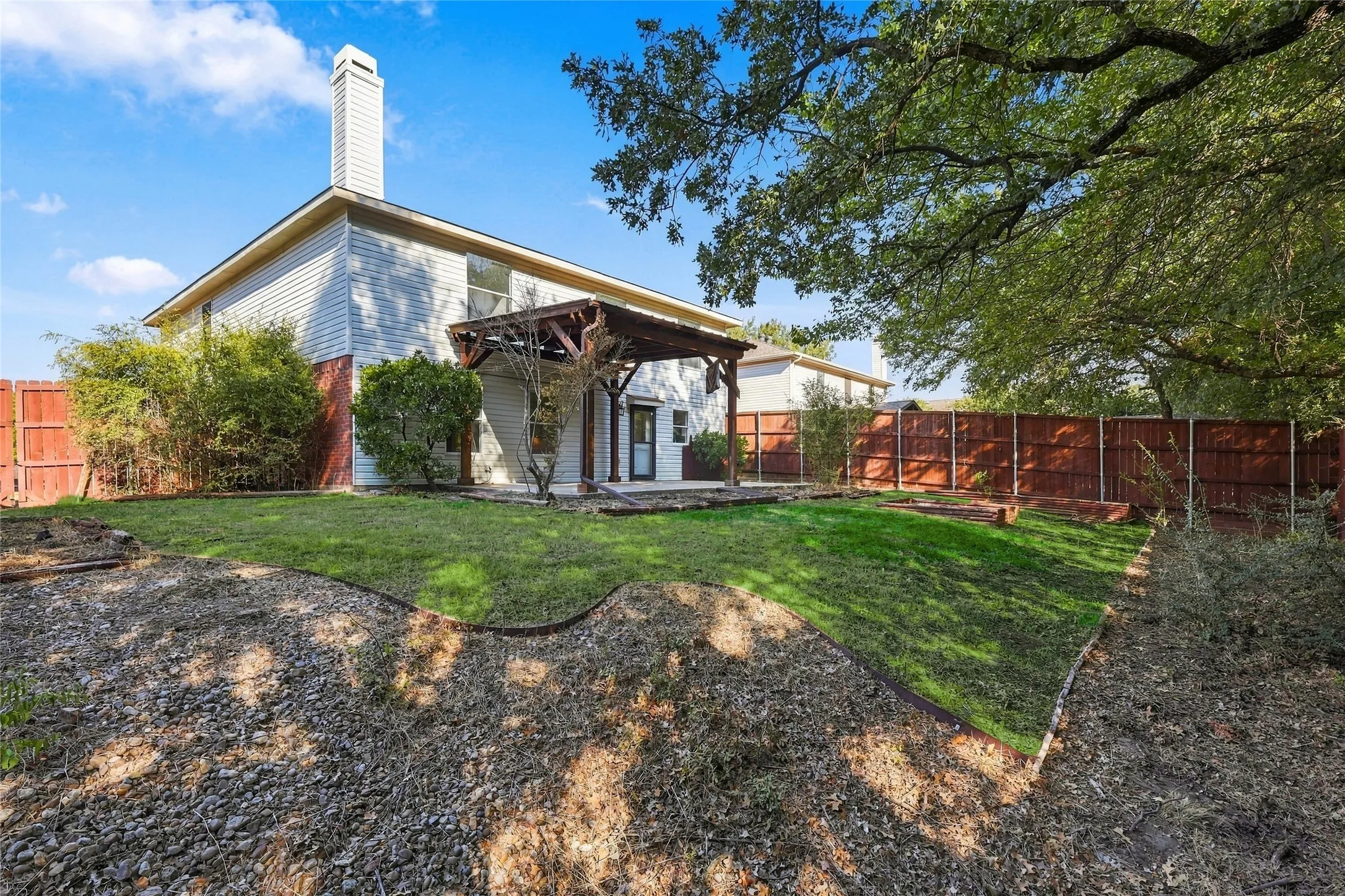 Expansive backyard featuring a manicured lawn, a wood pergola, and a privacy fence