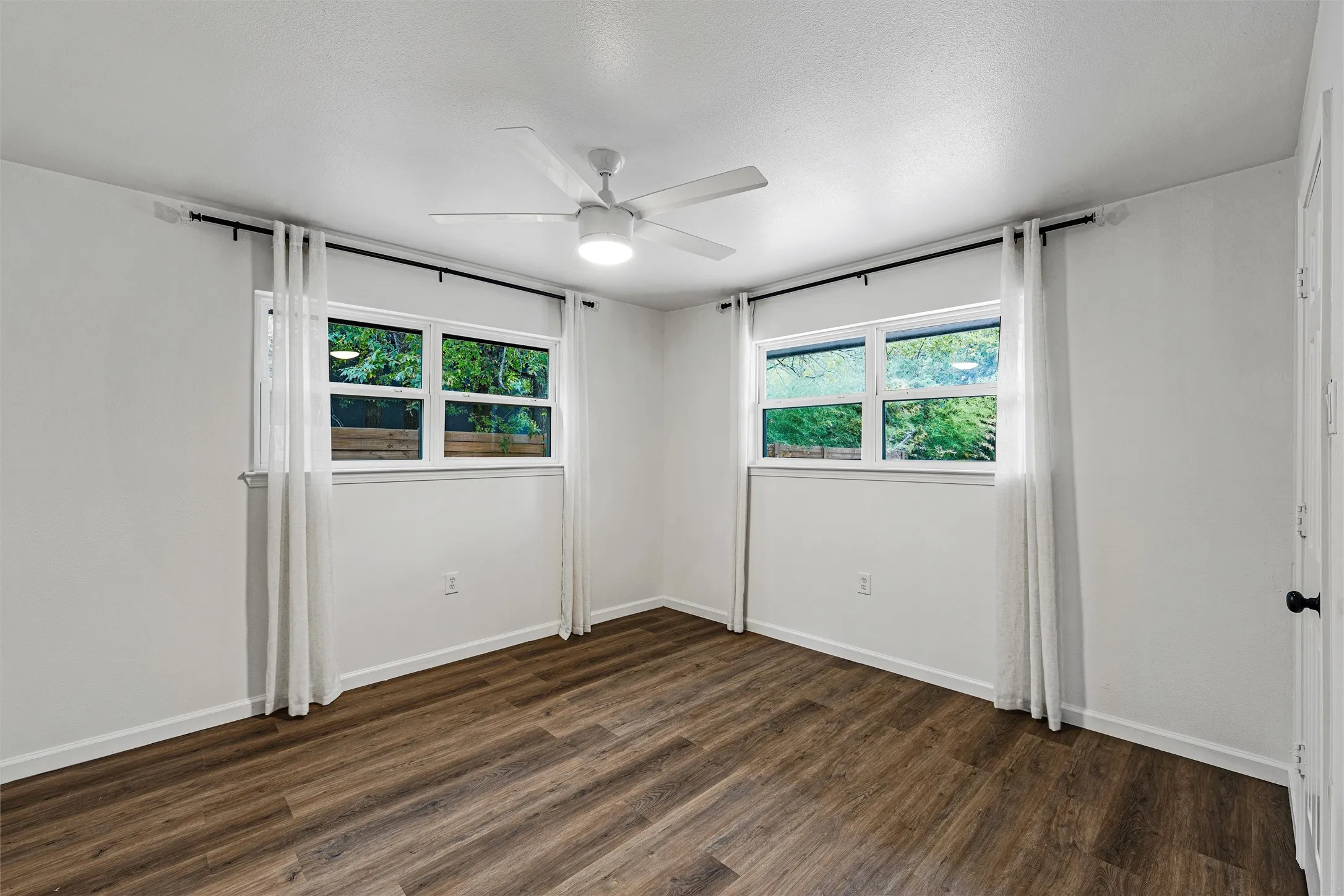 Wood-finish flooring, white walls, and a ceiling fan with integrated lighting