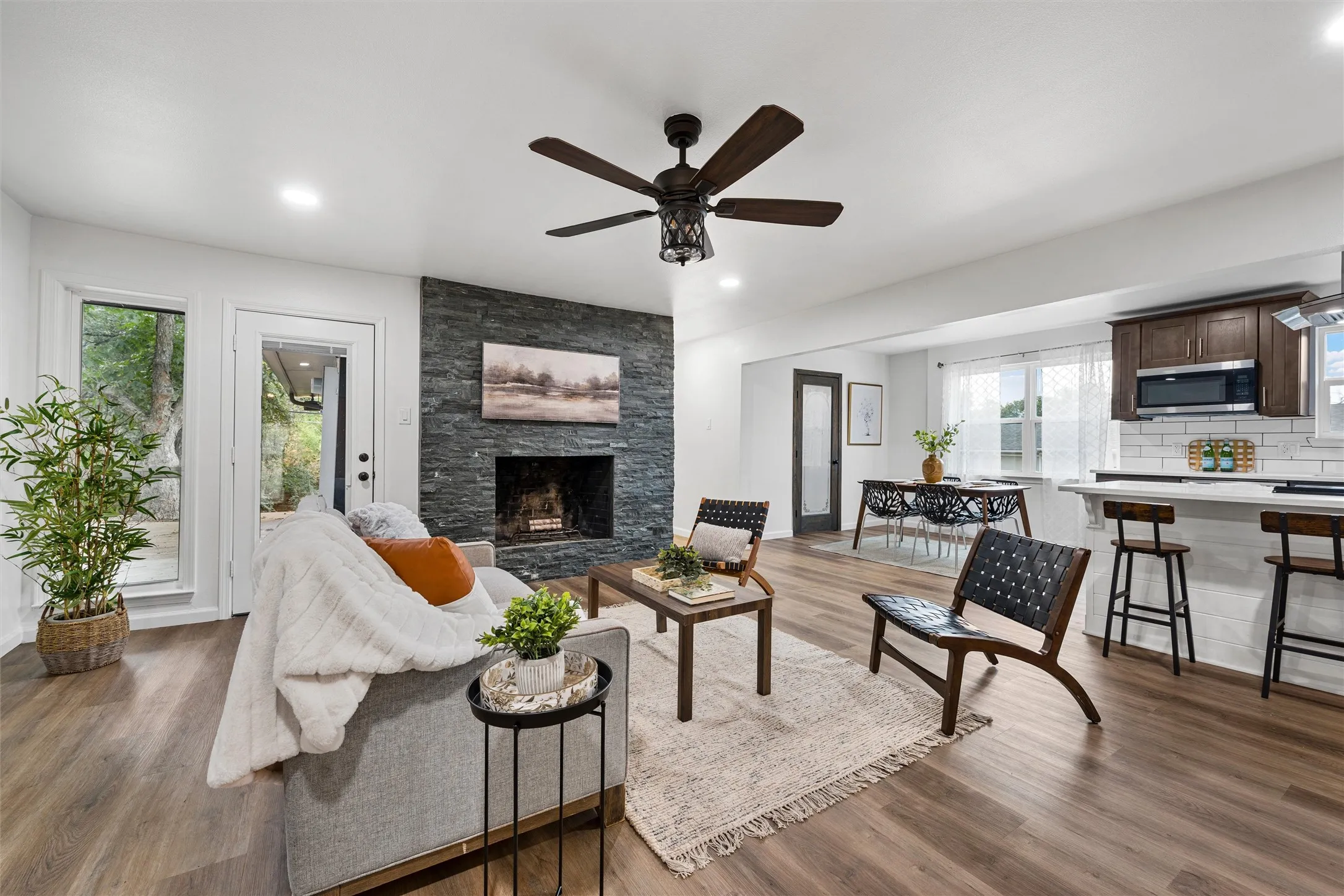 Wood-finish flooring throughout, a stone-faced fireplace, recessed lighting, and a ceiling fan