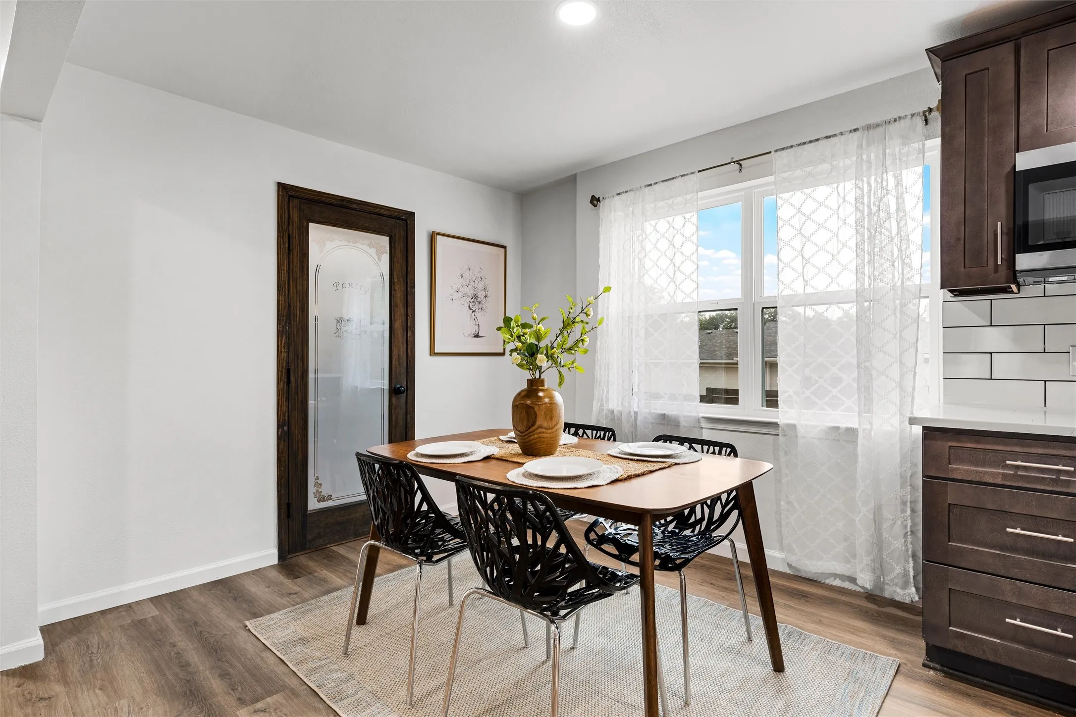 Wood-finish flooring with white walls and a dark wood door with frosted glass panel
