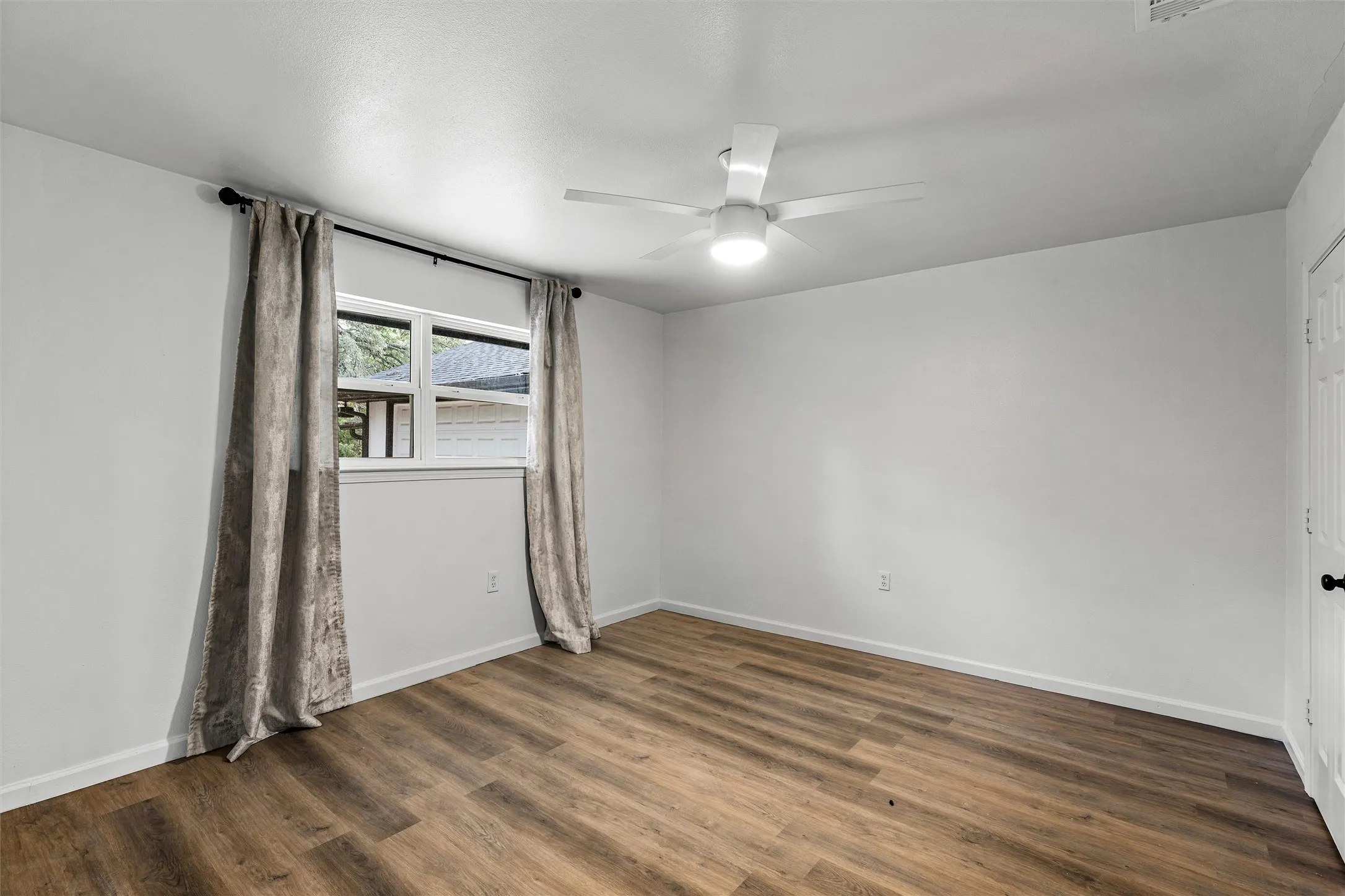 Wood-finish flooring, white walls, and a ceiling fan with integrated lighting