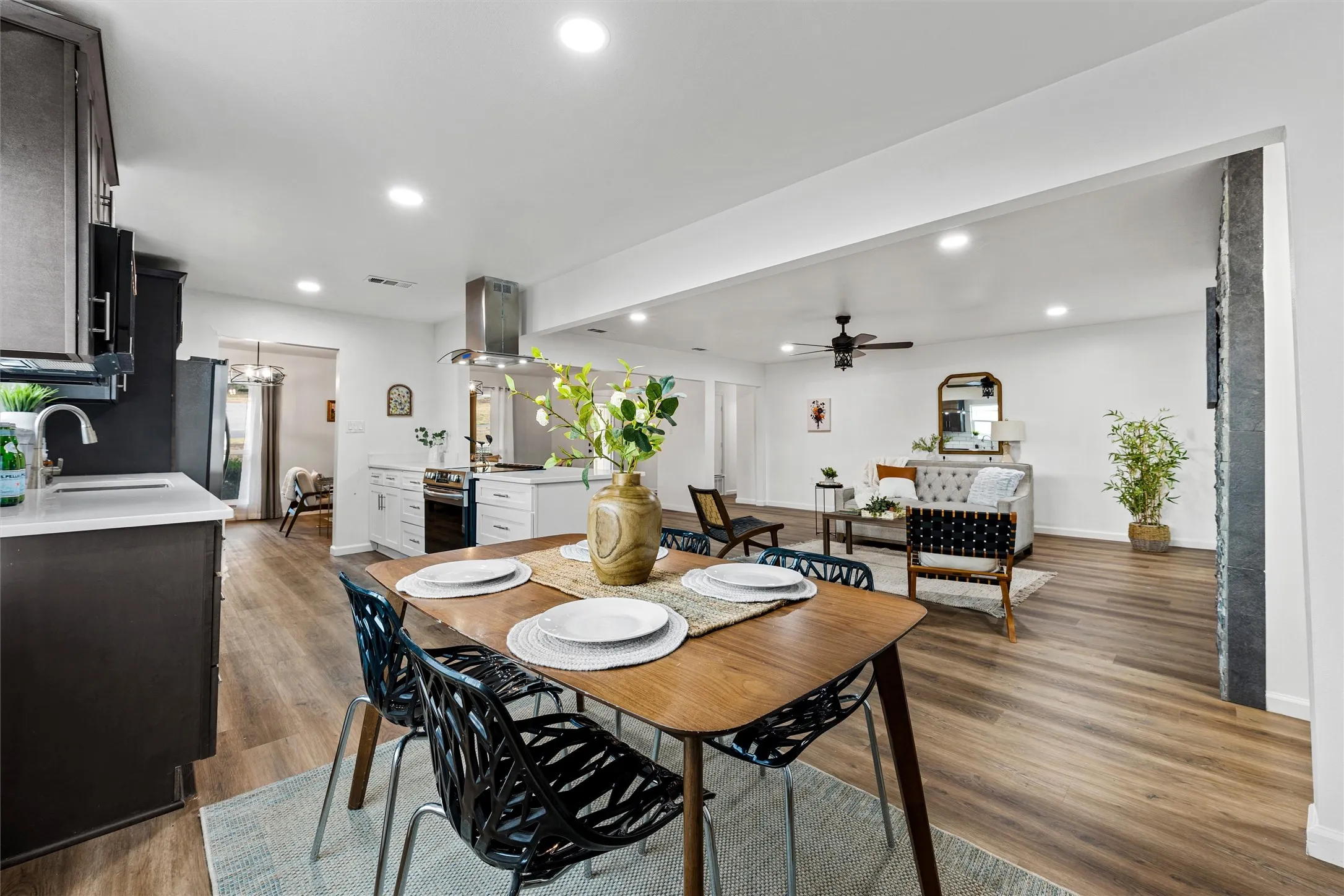 Open-concept living space featuring wood-finish flooring, recessed lighting, and a kitchen with a stainless steel range hood