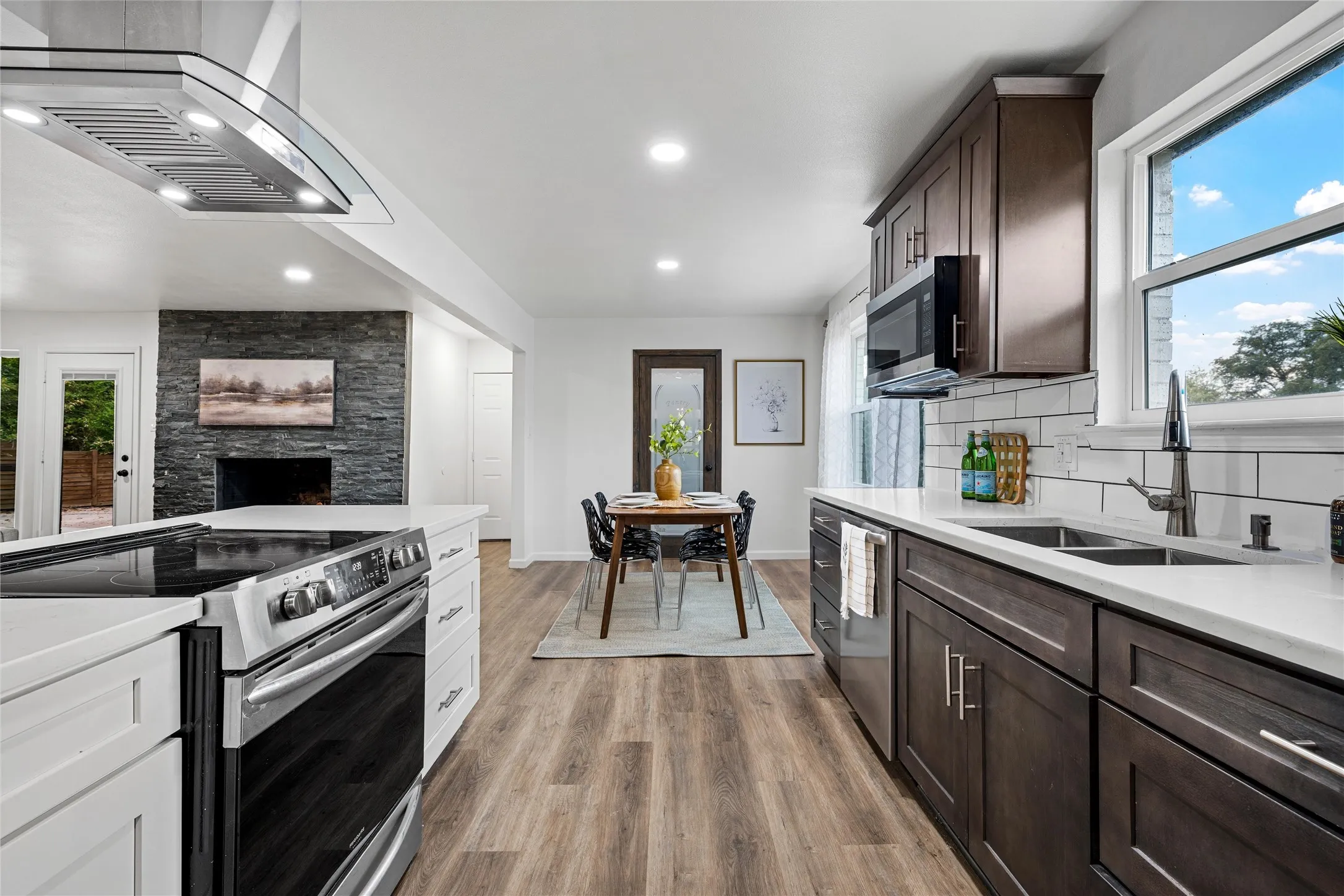 Bright kitchen featuring white countertops, stainless steel appliances, dark wood-finish cabinetry, and wood-finish flooring