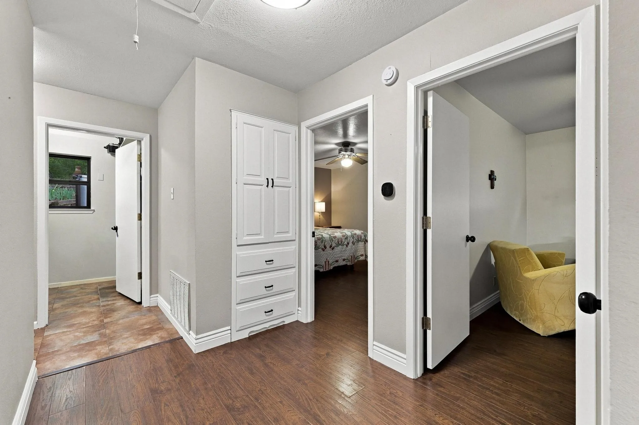 Wood-finish flooring throughout, bright white trim, and a built-in storage cabinet with multiple drawers and upper doors