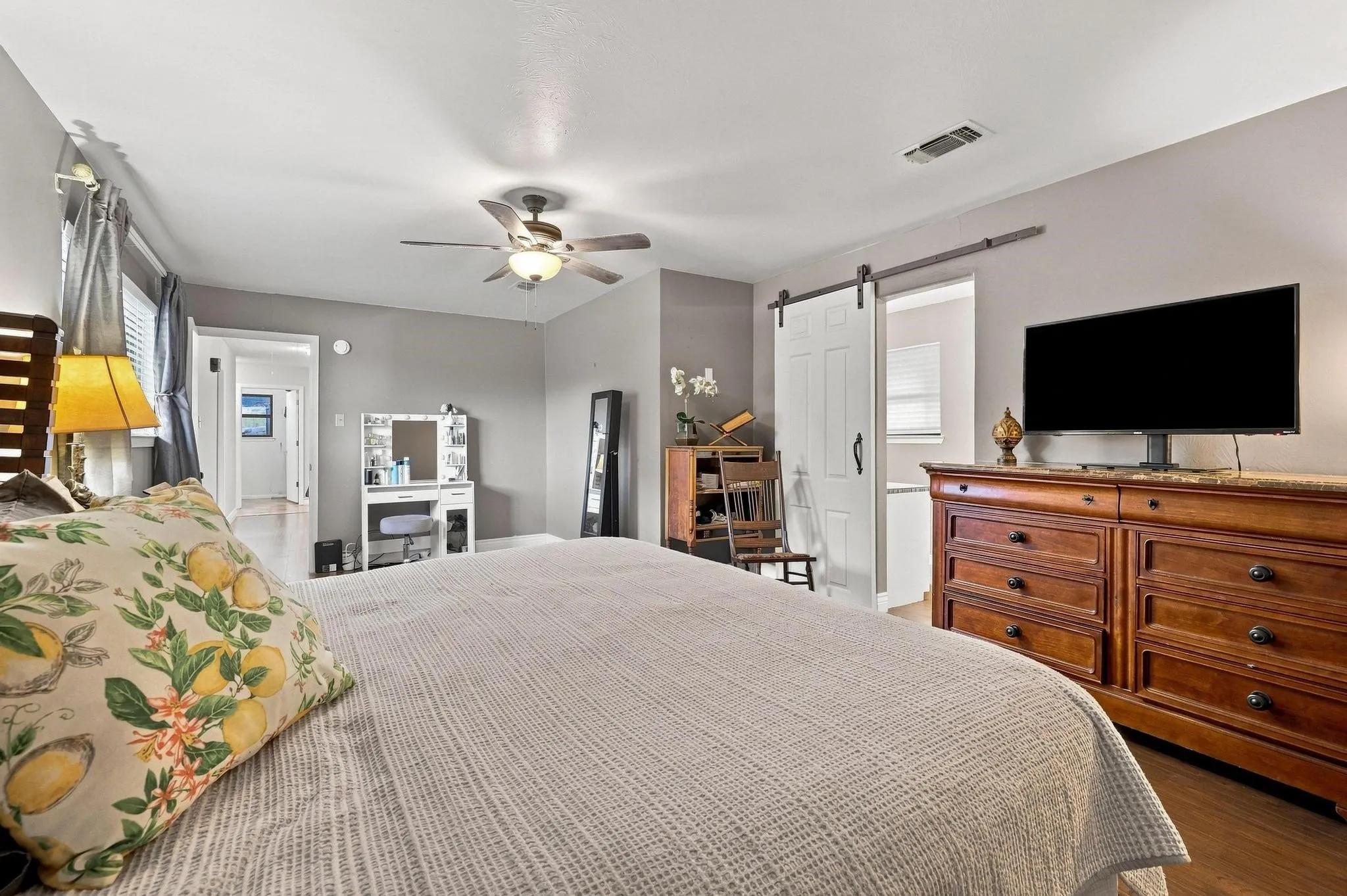 Ceiling fan with integrated lighting, wood-finish flooring, white paneled barn door, and a window with blinds