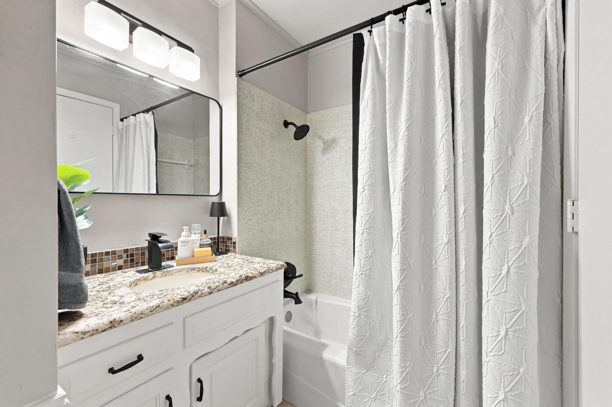 Vanity with granite countertop, integrated sink, and matte black faucet