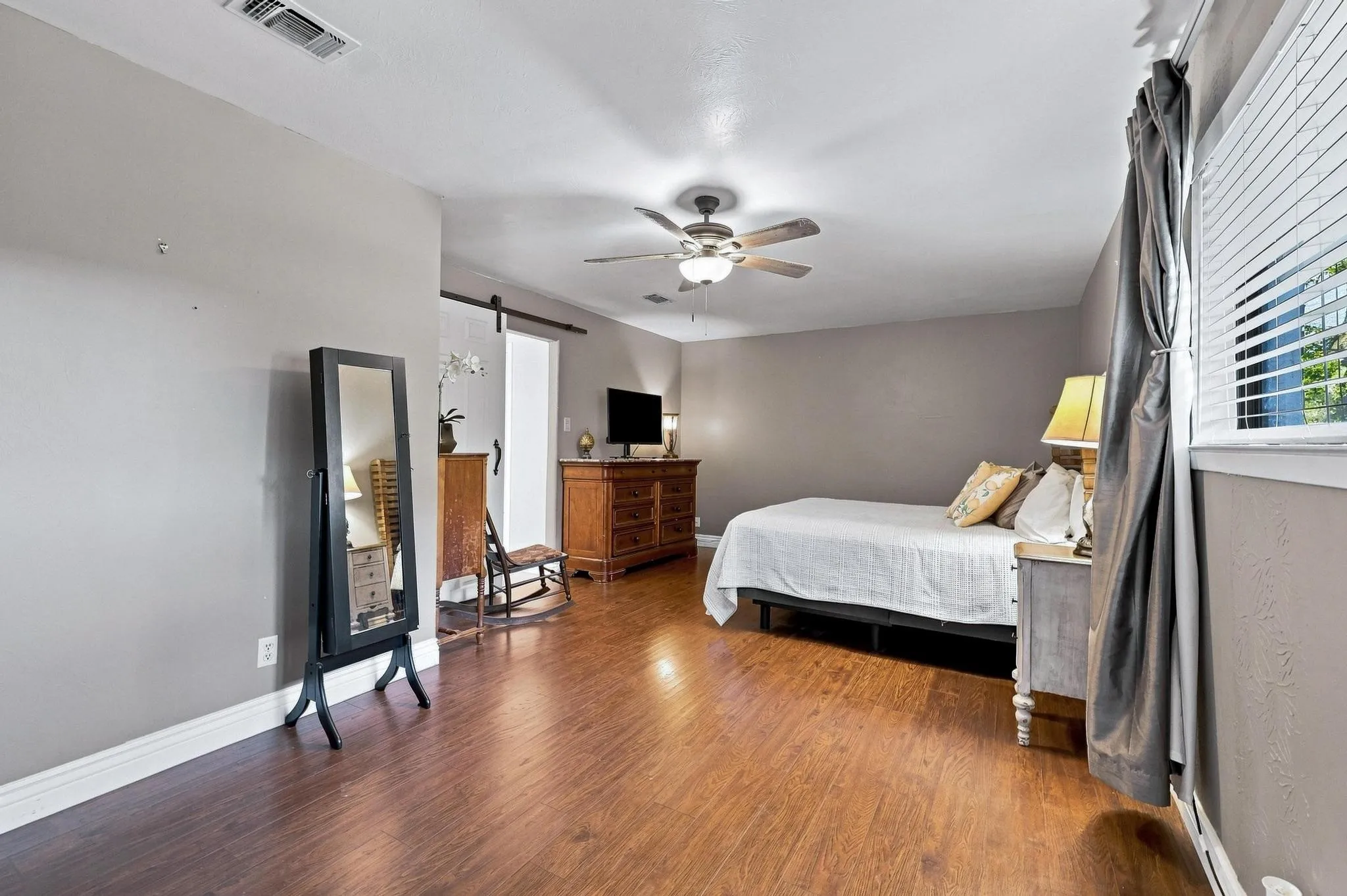 Wood-finish flooring throughout, ceiling fan with integrated lighting, and window with blinds