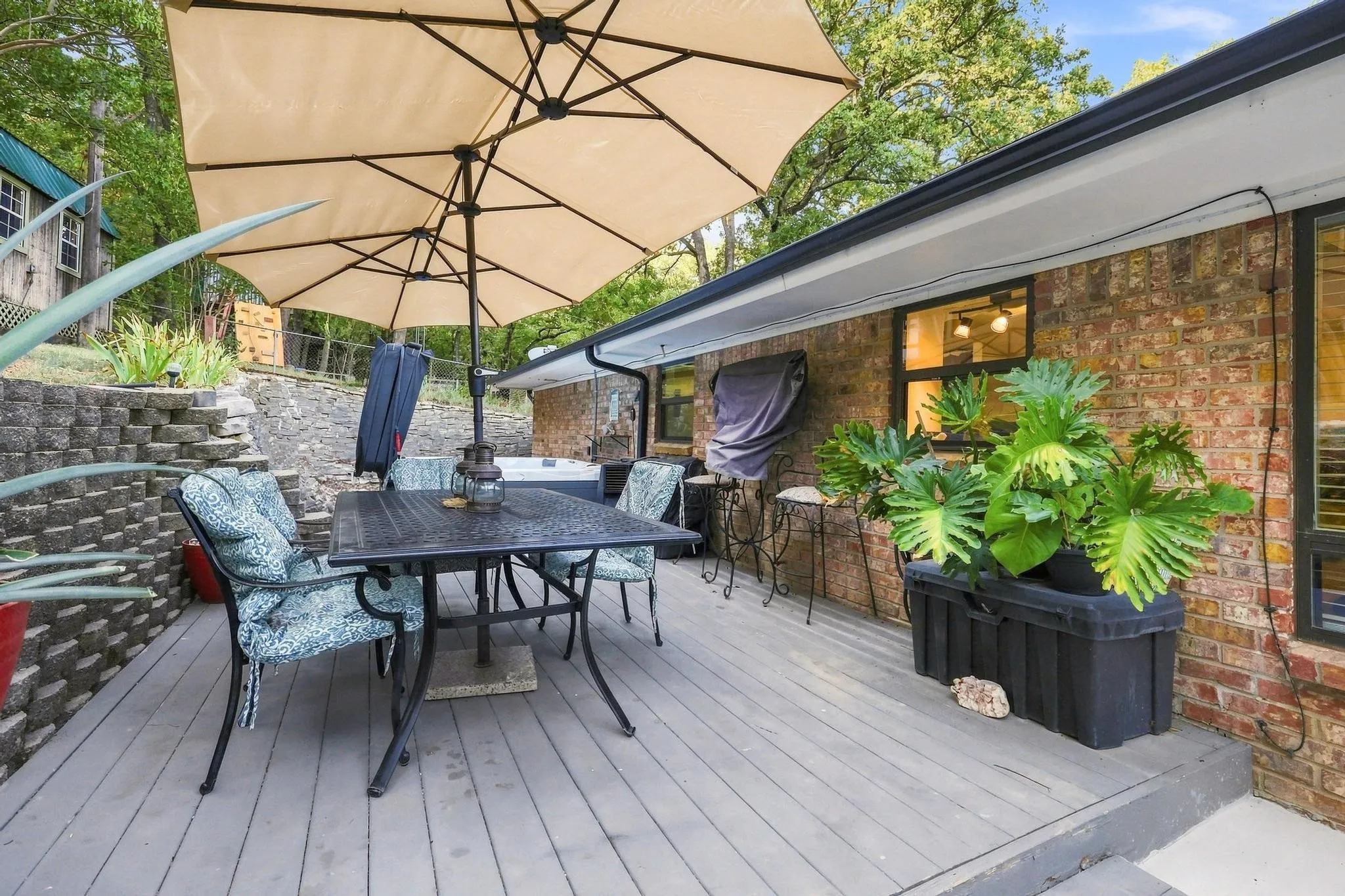 Expansive rear deck featuring gray wood-finish decking, brick exterior, and a built-in spa