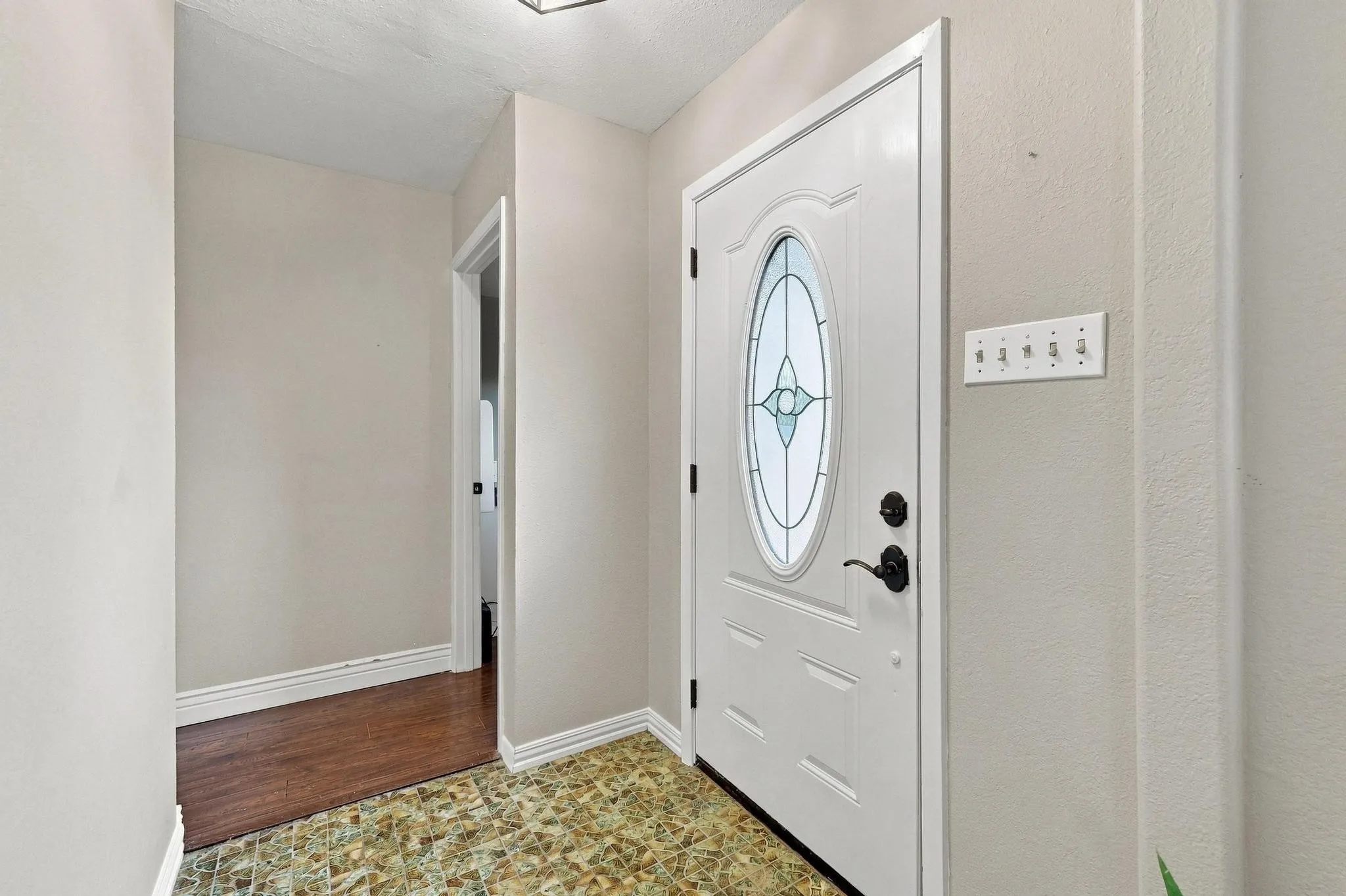 White entry door with decorative oval glass insert and matte black hardware