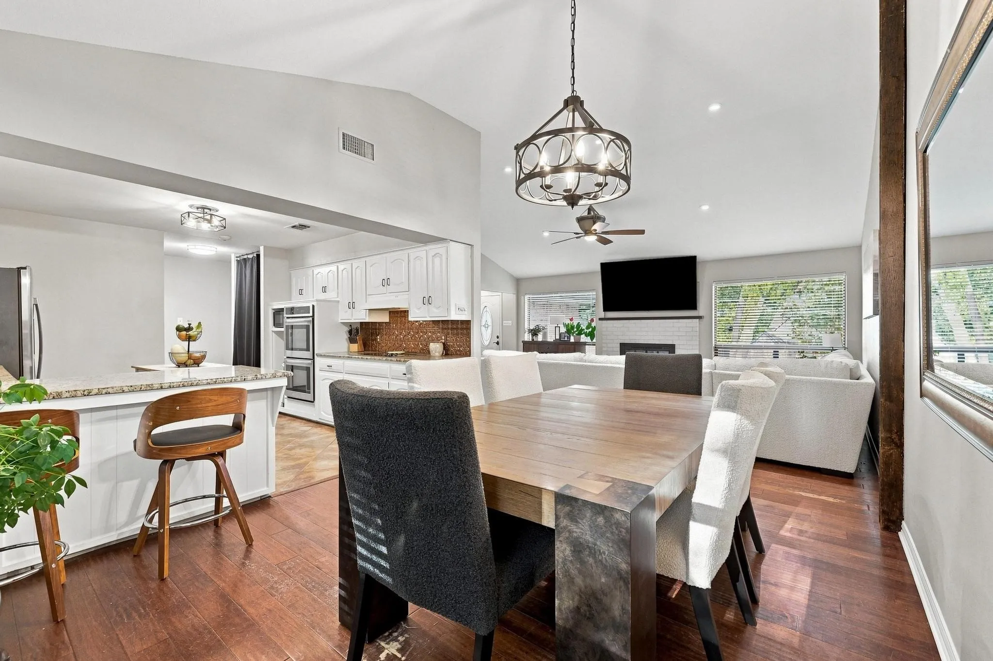 Vaulted ceilings, wood-finish flooring, white cabinetry, built-in double oven, and recessed lighting